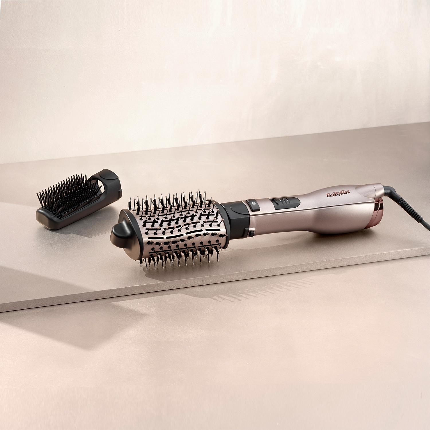 Uno strumento per lo styling dei capelli con due accessori su una superficie neutra.