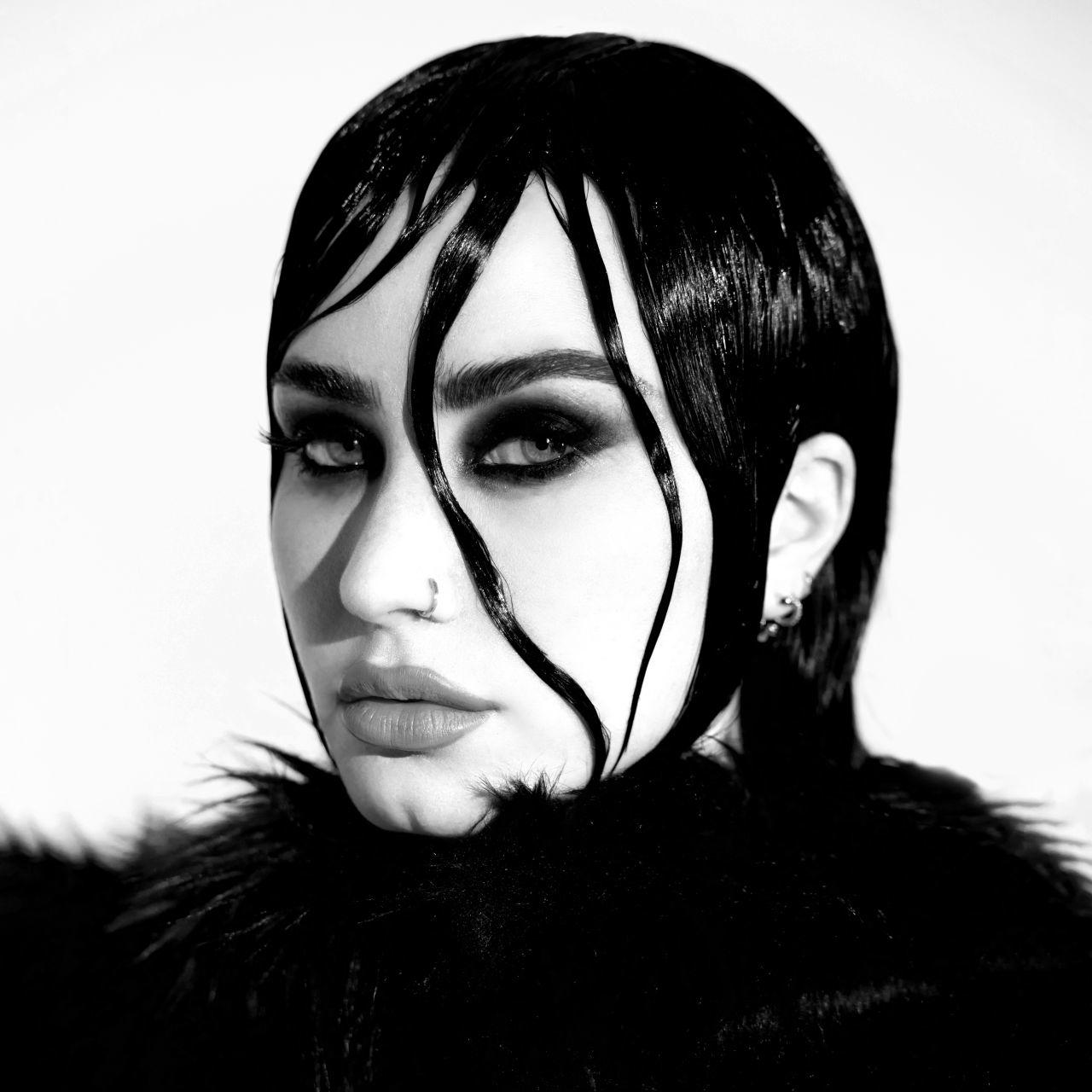 Ein Frauenporträt in Schwarzweiß. Sie hat dunkles Make-up, gegeltes Haar und einen Nasenring.