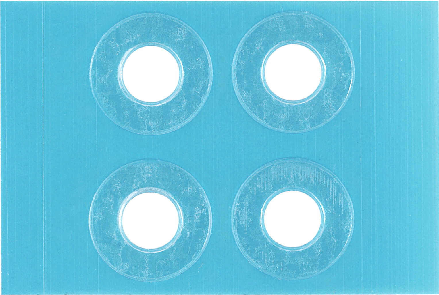 Quatre autocollants bleus circulaires avec centres blancs. La surface est mate.