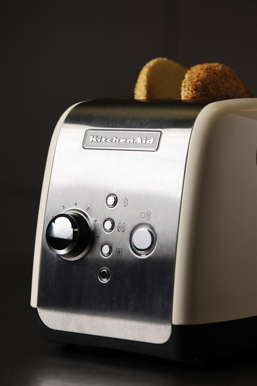 Krémszínű és ezüst KitchenAid kenyérpirító kenyérszeletekkel.