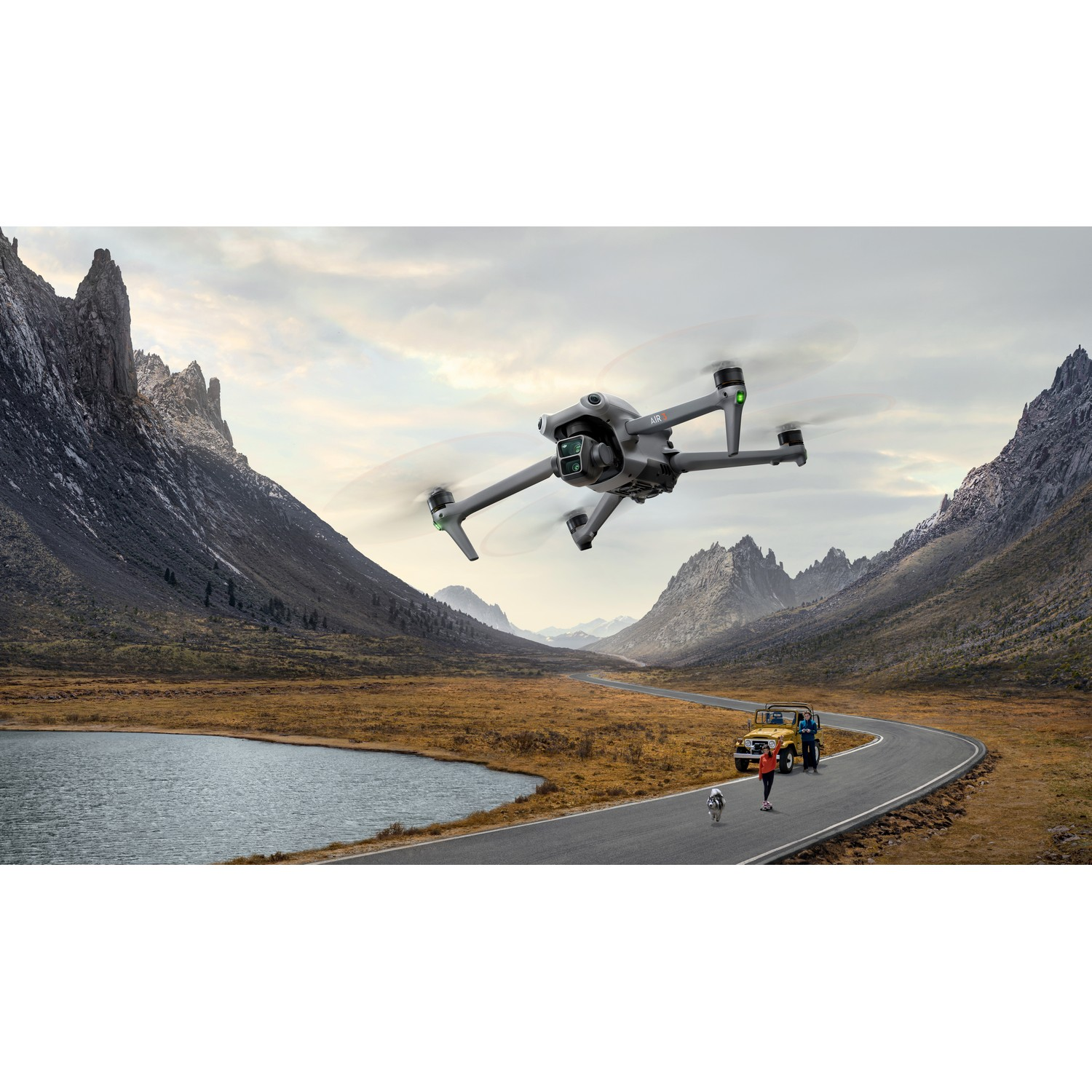 Een drone die vliegt in een schilderachtig landschap met bergen, een weg en mensen, in een bewolkte omgeving.