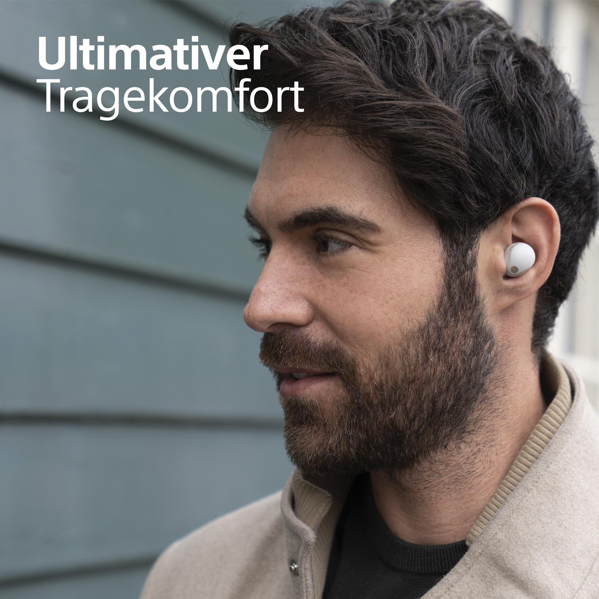 Mann mit weißen Ohrhörern, der eine Jacke trägt.