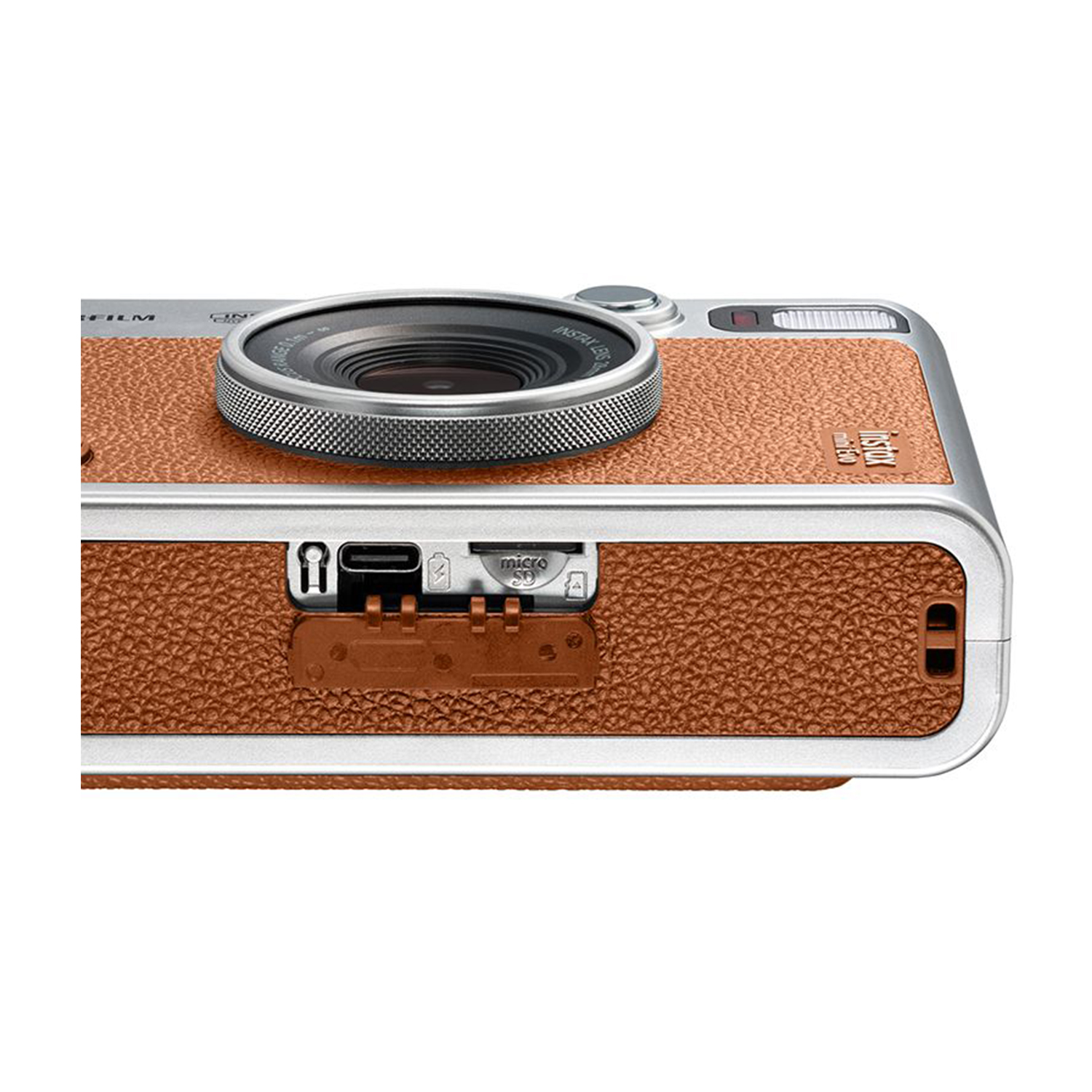 Primo piano del lato di una fotocamera Instax, che mostra l'obiettivo, le porte e una trama in pelle marrone.