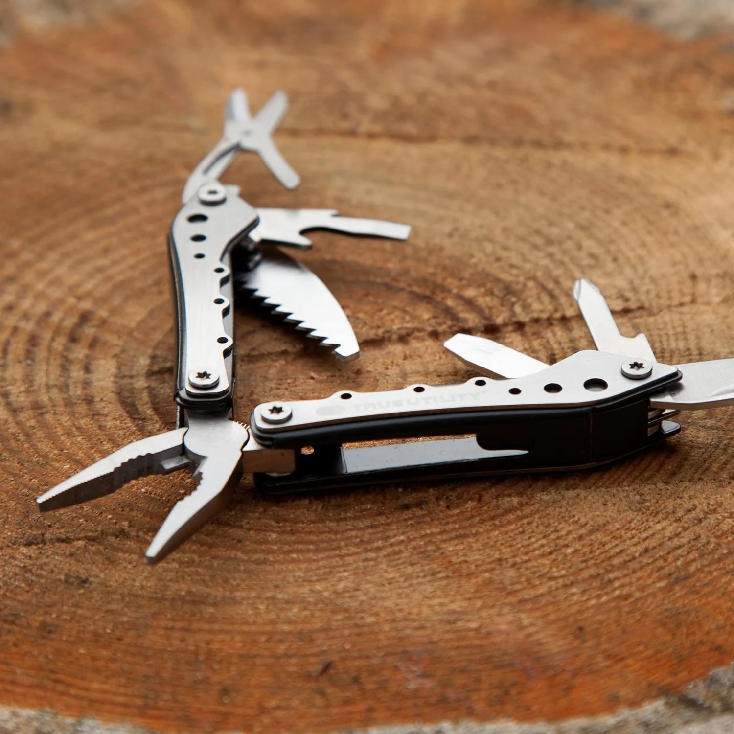 Ein Multitool-Messer auf einer Holzoberfläche. Es ist teilweise geöffnet, mit Zange und Säge sichtbar.