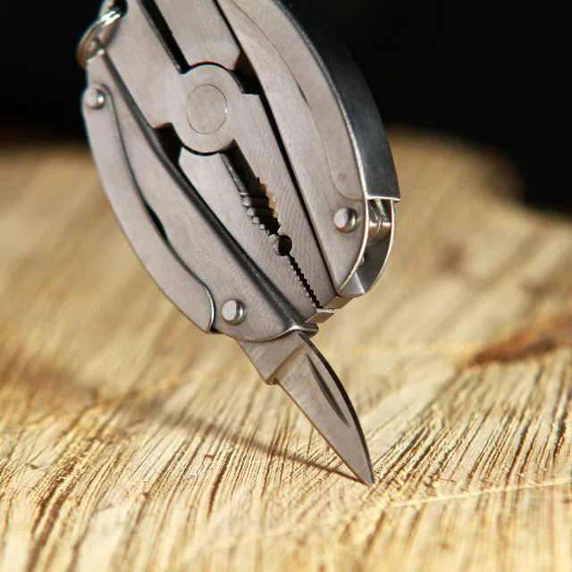 Multitool mit Zange und kleinem Messer auf Holz.