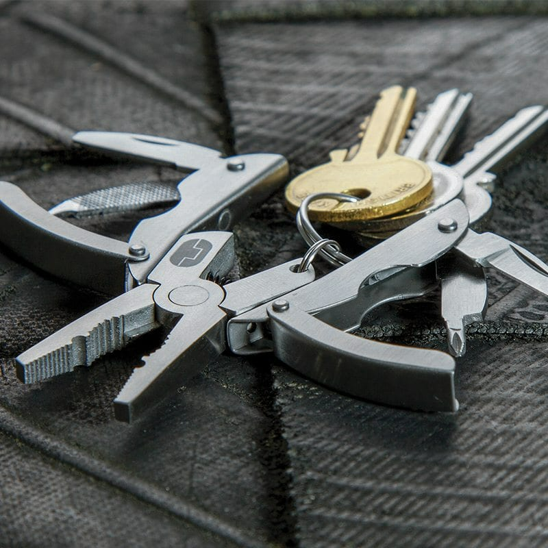 Ein Multitool, teilweise geöffnet, mit Schlüsseln oben. Das Multitool befindet sich auf einer strukturierten Oberfläche.