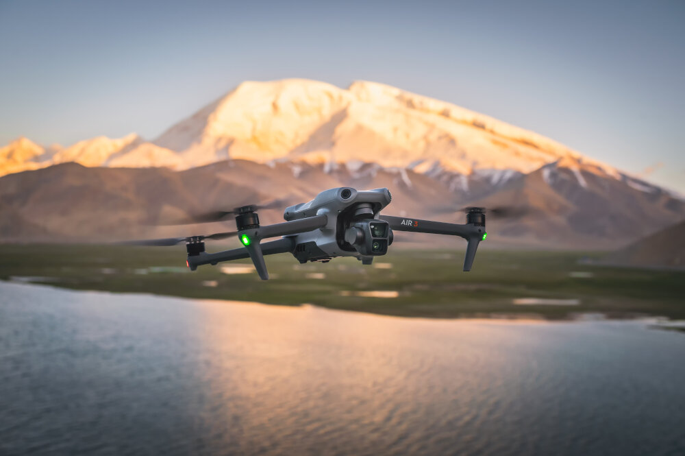 Dron lecący nad jeziorem z górami w tle.