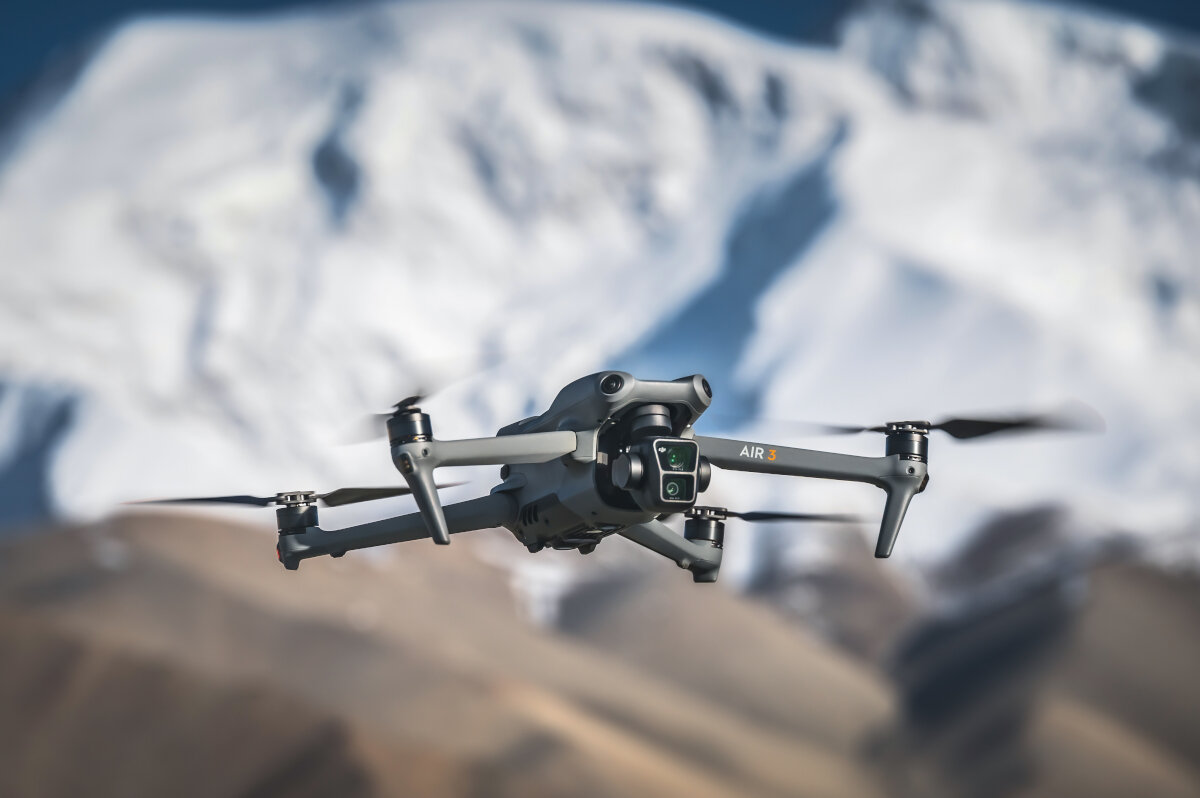 Dron lecący na tle ośnieżonego pasma górskiego.