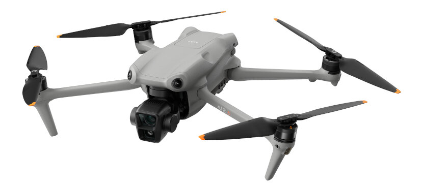 Szary dron z czarnymi śmigłami, kamerą i podwoziem na białym tle.