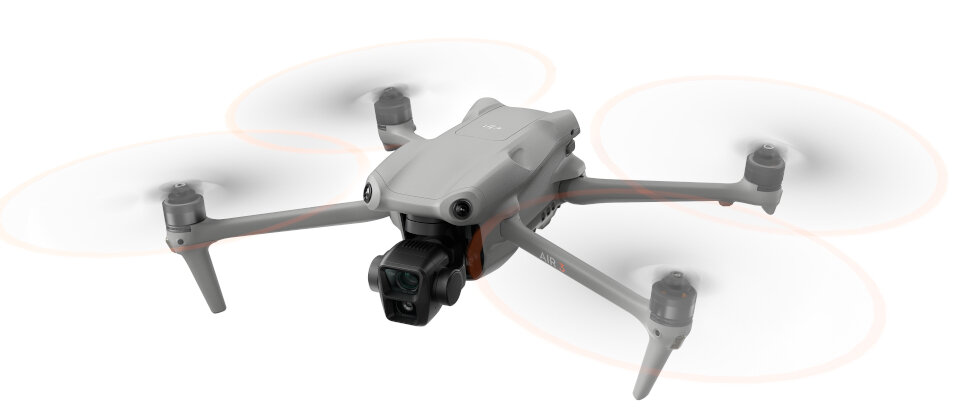 Szary dron z wirującymi śmigłami na białym tle. Widoczna kamera i czujniki.