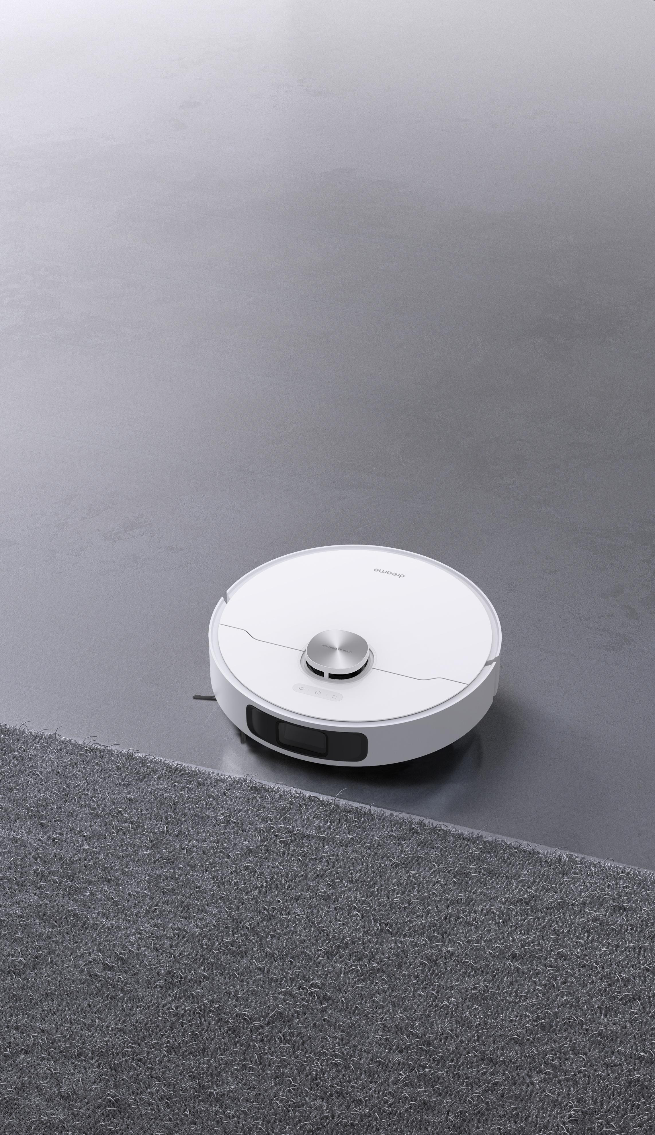 Weißer Roboter-Staubsauger auf grauem Boden, in der Nähe eines Teppichs.