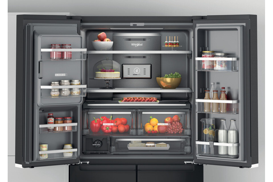 Otwarta lodówka wypełniona jedzeniem. Widać owoce, warzywa i słoiki.