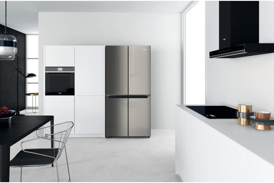 Nowoczesna kuchnia z białymi szafkami, lodówką ze stali nierdzewnej i czarną płytą grzewczą.