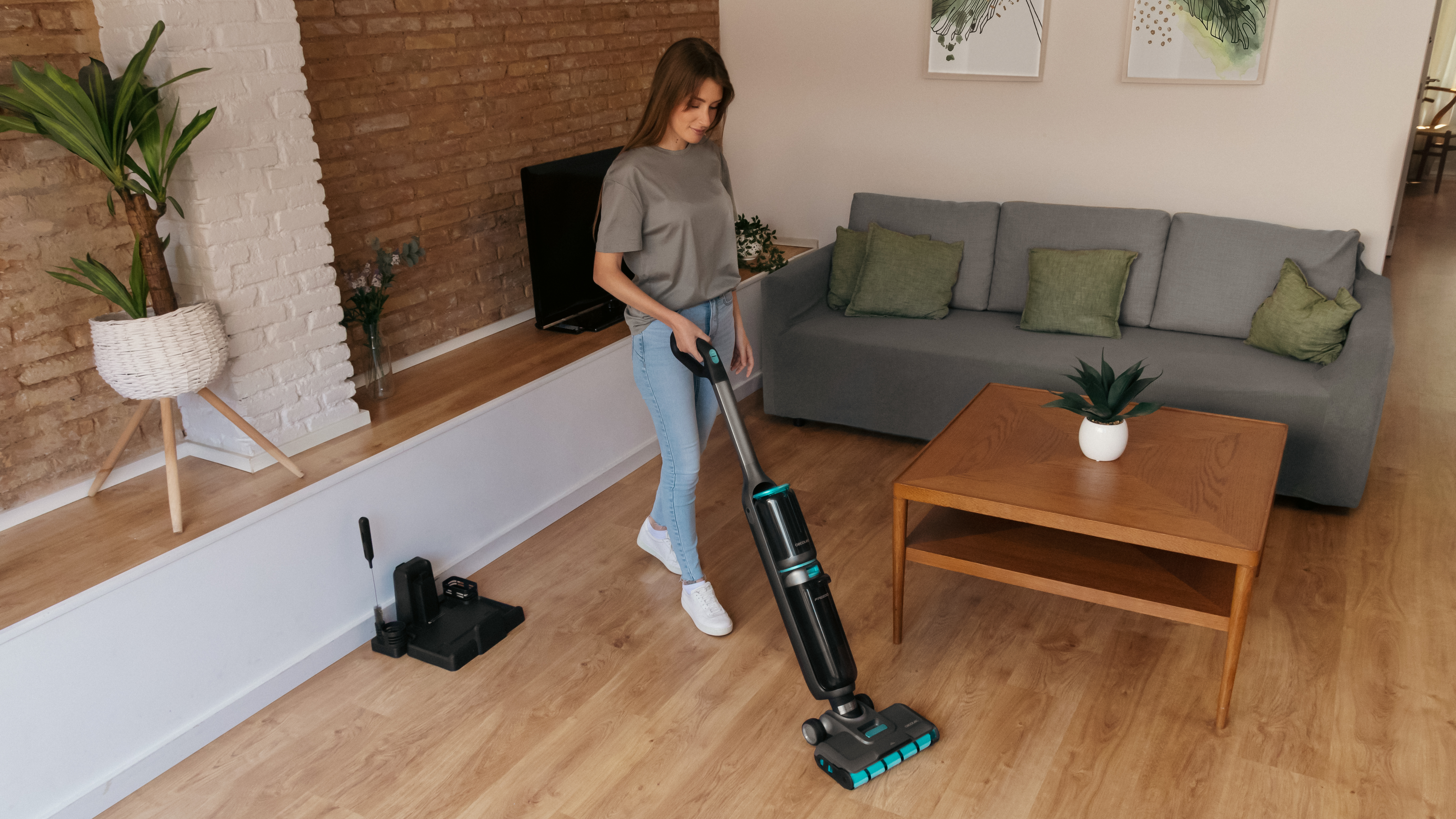 Una mujer aspira una sala de estar con una moderna aspiradora inalámbrica.