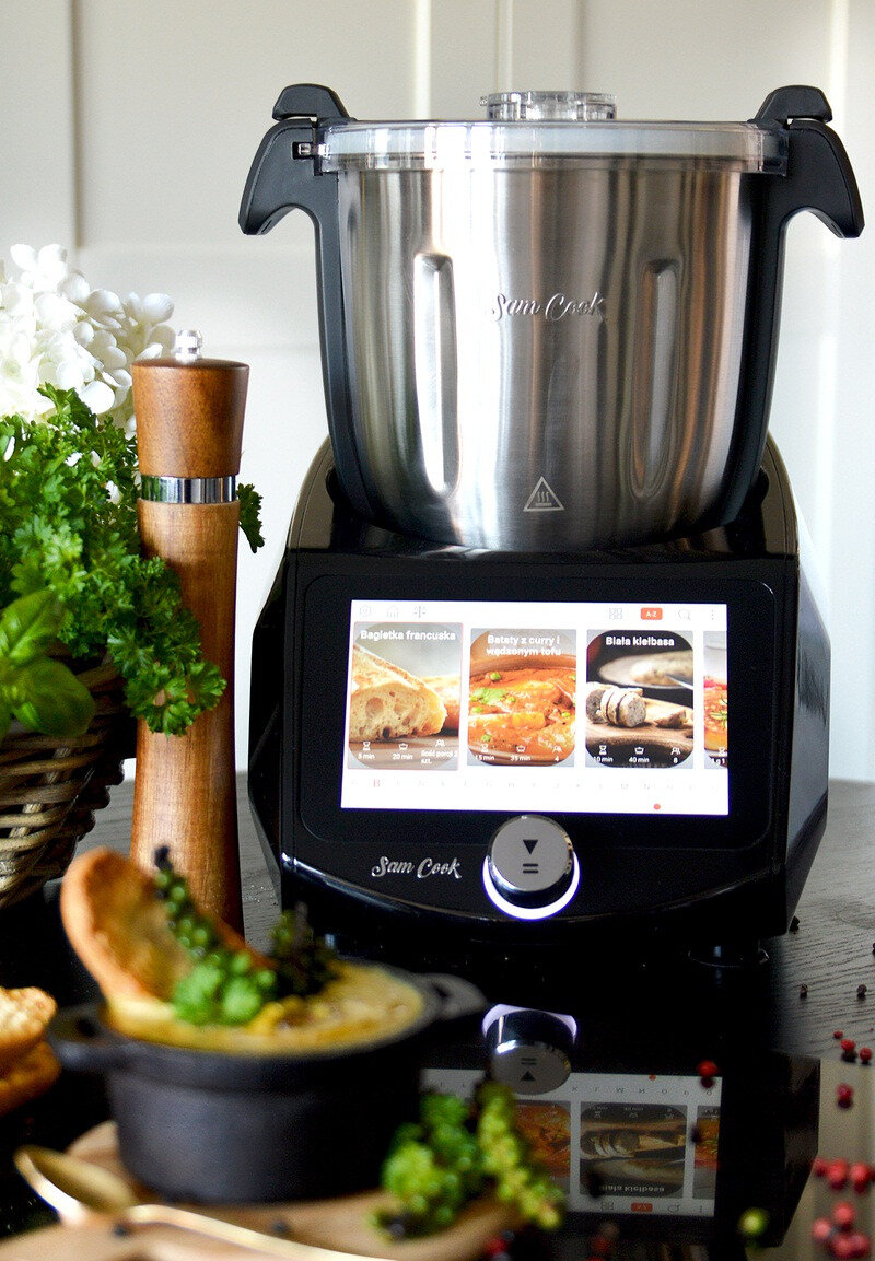 Robot kuchenny Sam Cook z czarnym ekranem wyświetlającym przepisy. Jedzenie jest na pierwszym planie.