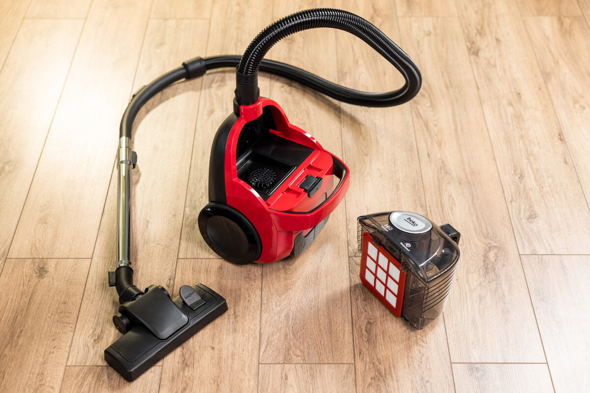 Czerwono-czarny odkurzacz z odłączonym pojemnikiem na kurz.