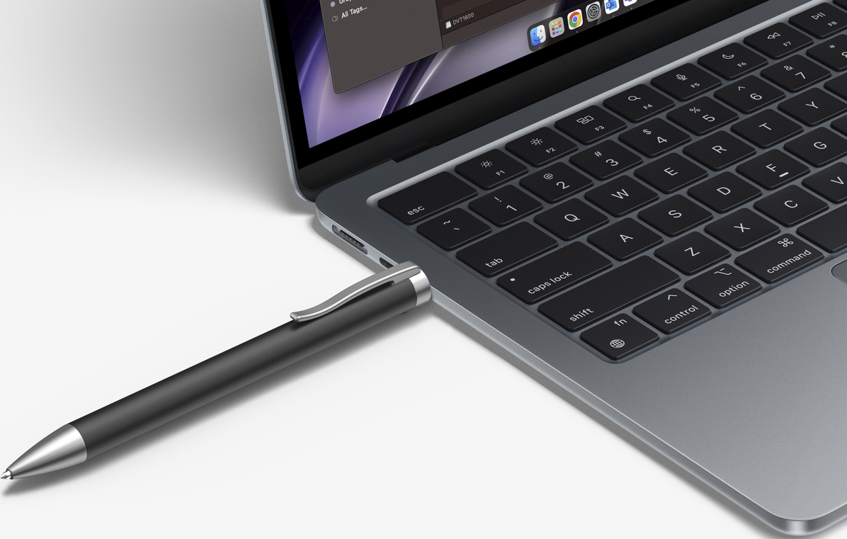 Un stylo argenté branché sur un ordinateur portable sur une surface blanche.