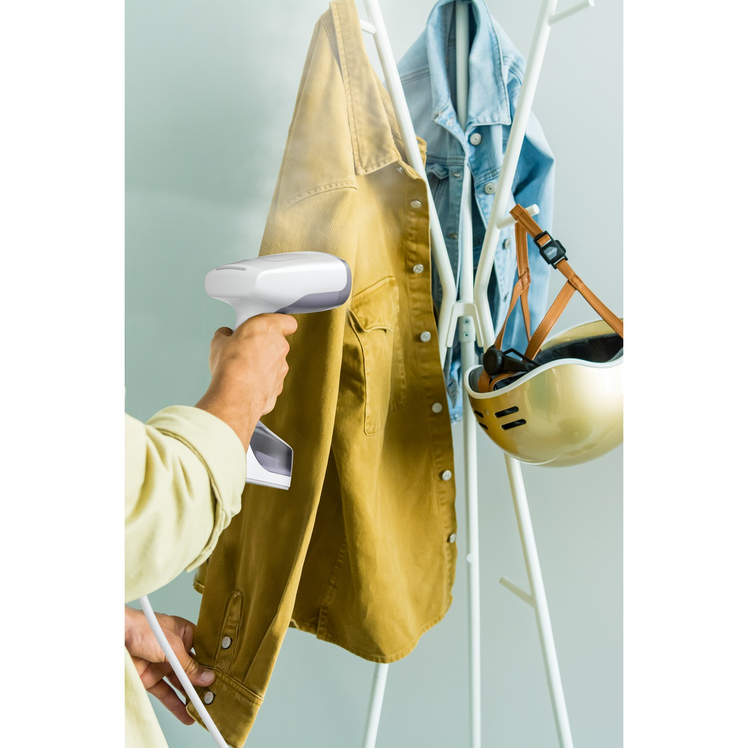 Homme repassant une veste jaune. Fond blanc.