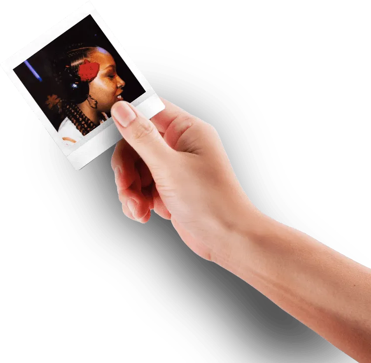 Une main tenant une photo Polaroid d'une femme avec une fleur rouge dans les cheveux.