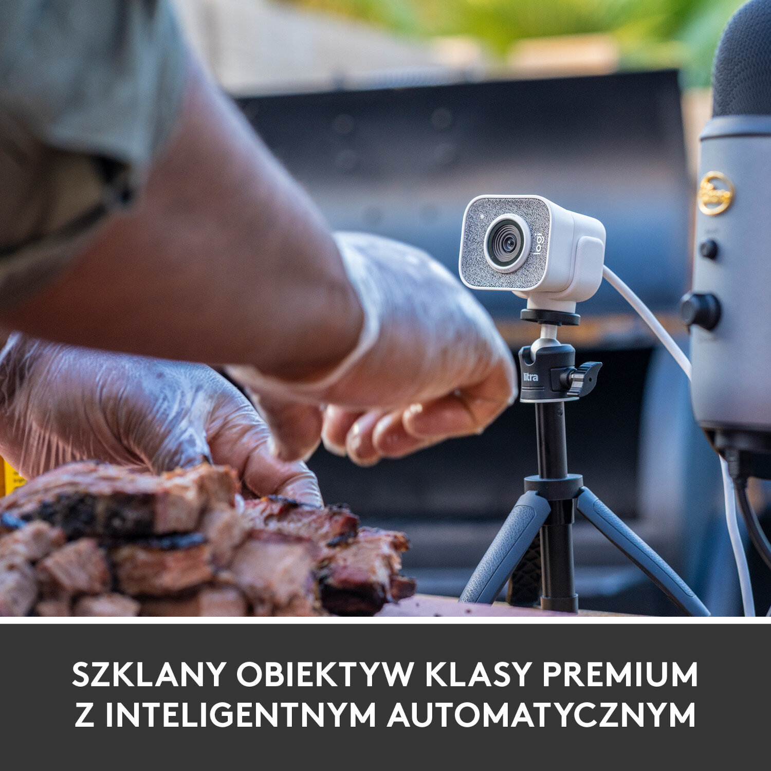 Kamera internetowa na statywie używana obok mikrofonu i grillowanego jedzenia.