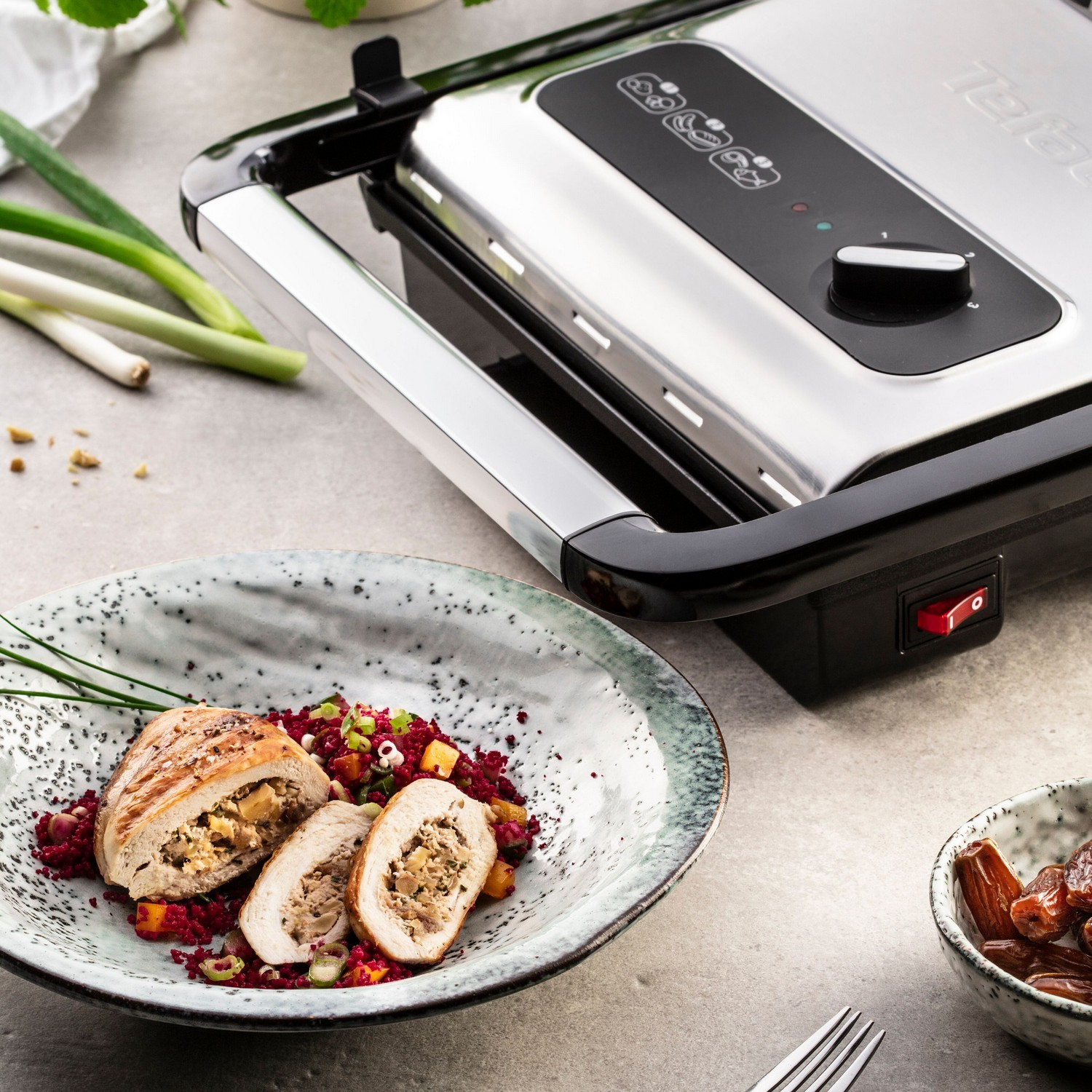 Un grill avec de la nourriture sur une assiette. L'assiette contient du poulet et une garniture rouge.