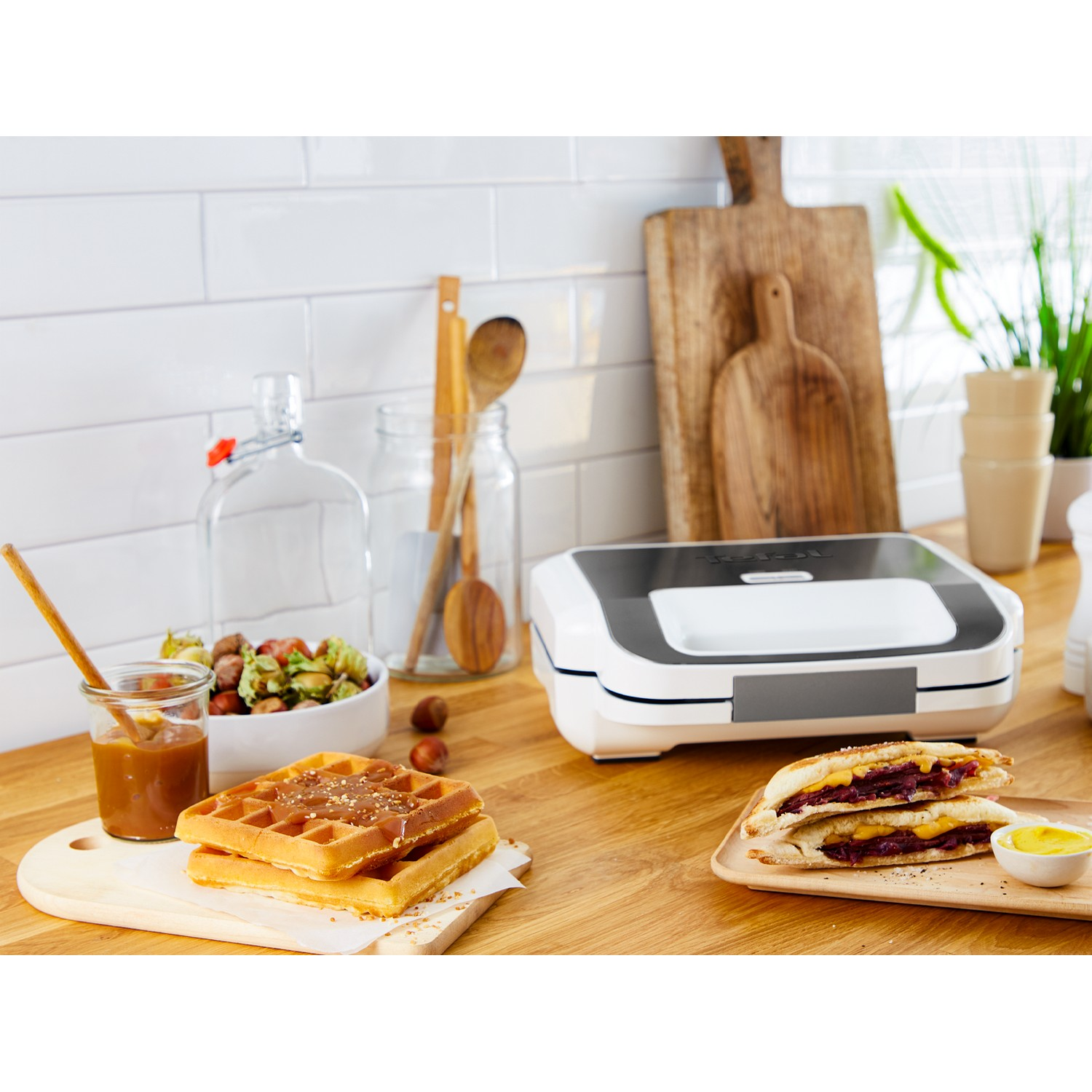 A kitchen counter with waffles, a sandwich, and other kitchenware.