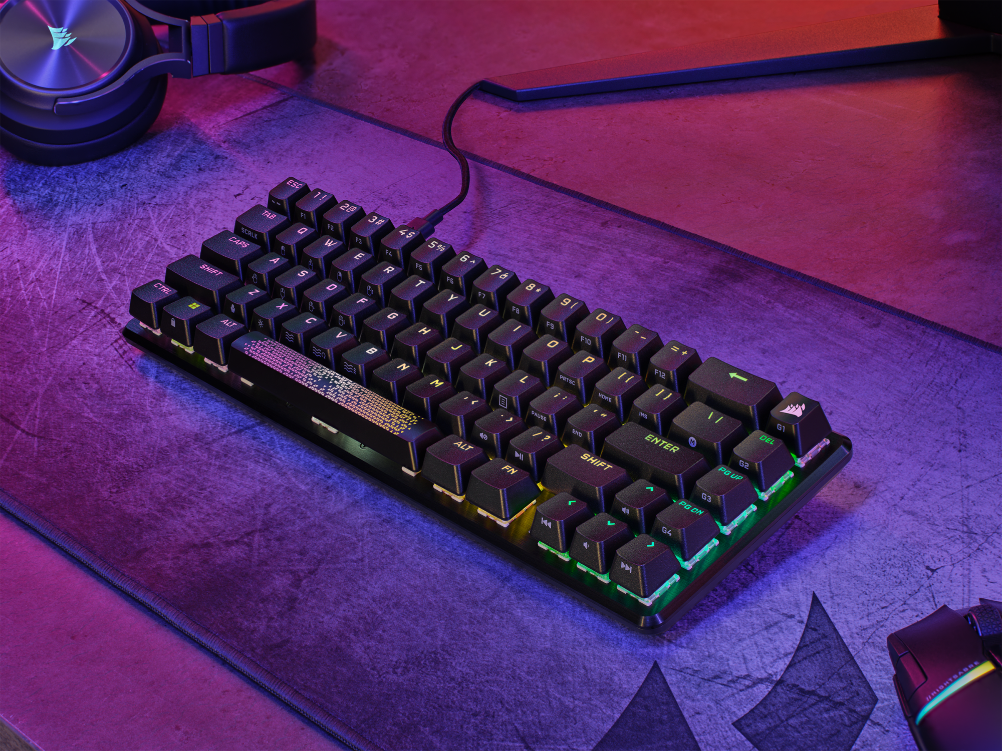Eine kleine, hinterleuchtete Tastatur auf einem lila beleuchteten Schreibtisch. Die Tastatur ist schwarz.