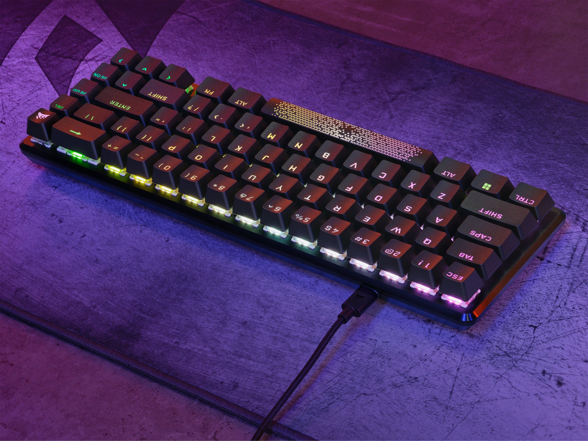Eine schwarze und farbenfrohe Tastatur. Mehrfarbige Tasten. Schwarze Basis. Ein Ladekabel ist angeschlossen.