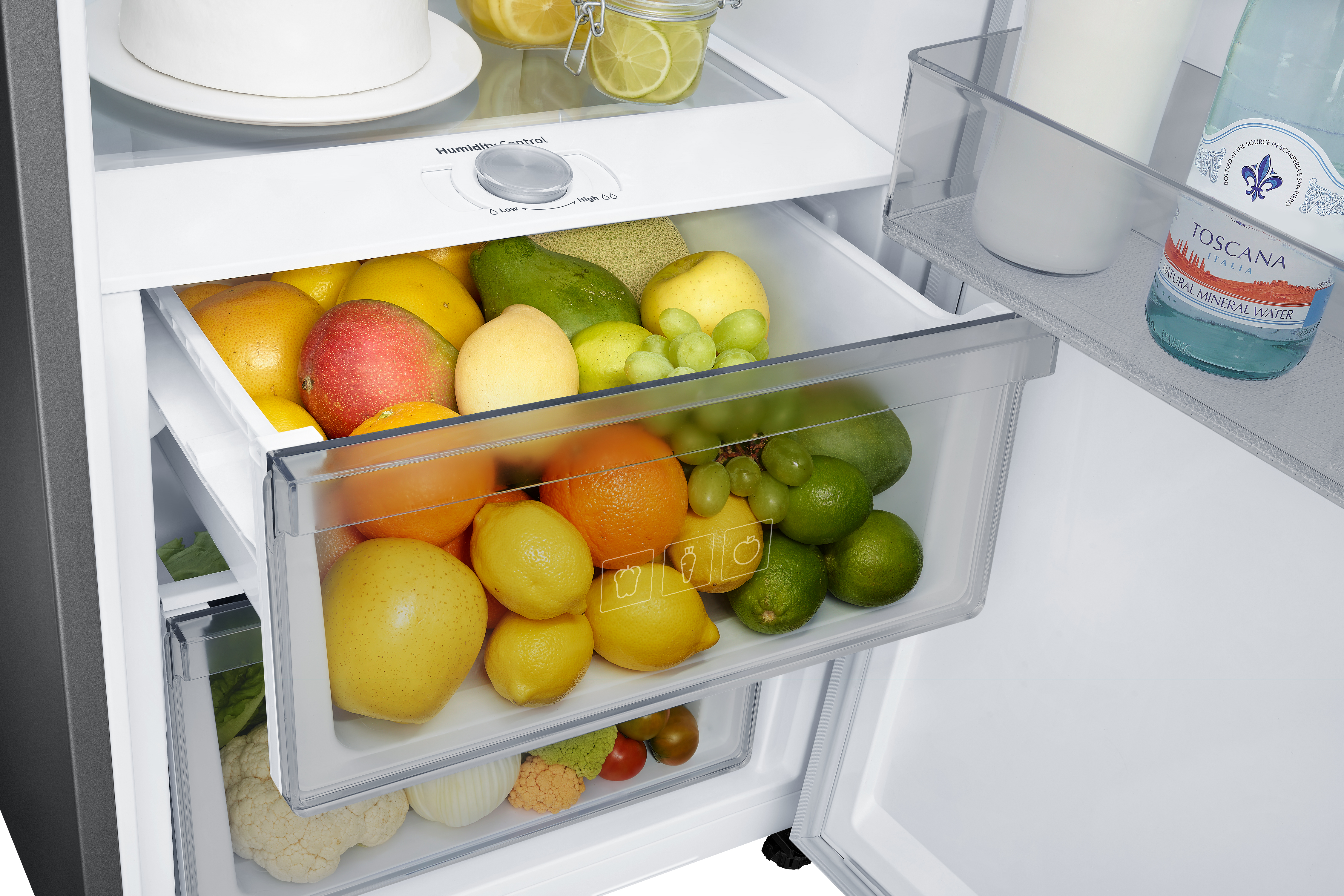 Cajón de refrigerador lleno de frutas. Limones, naranjas y otros productos.