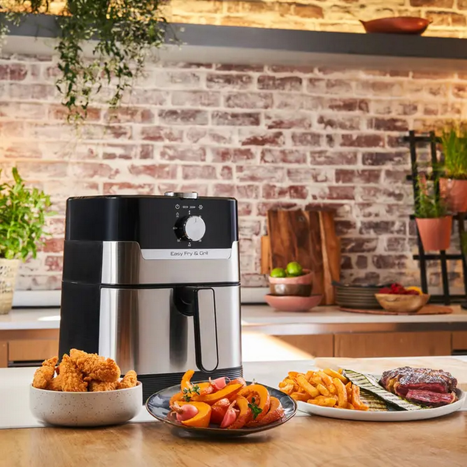 An air fryer with food on plates in front of a brick wall.