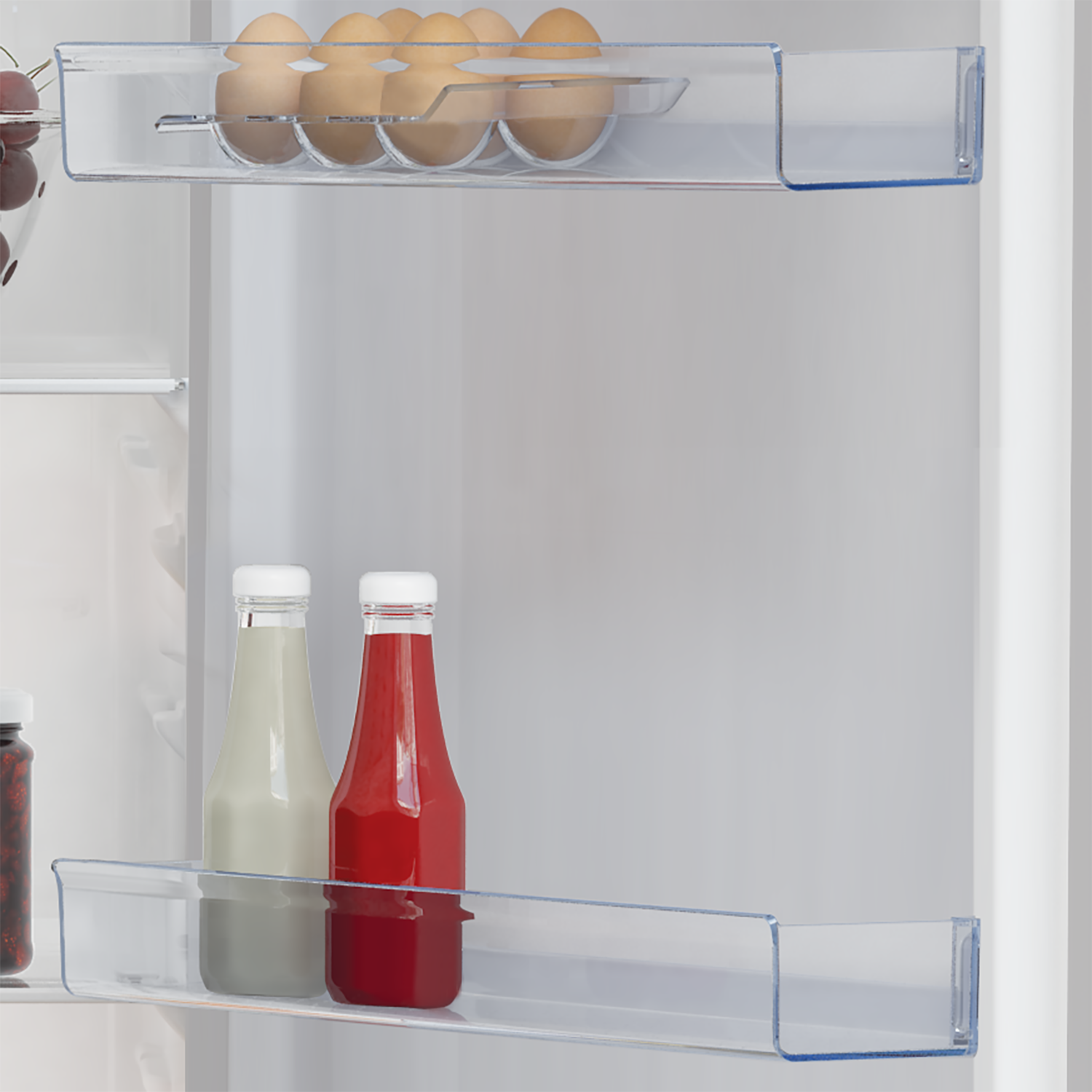 Refrigerator with eggs, and bottles of sauce in the door shelves.