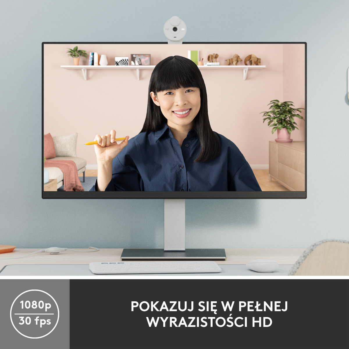 Kobieta w niebieskiej koszuli trzyma żółty długopis na monitorze. Nad monitorem kamera internetowa. Tekst: 1080p 30fps.