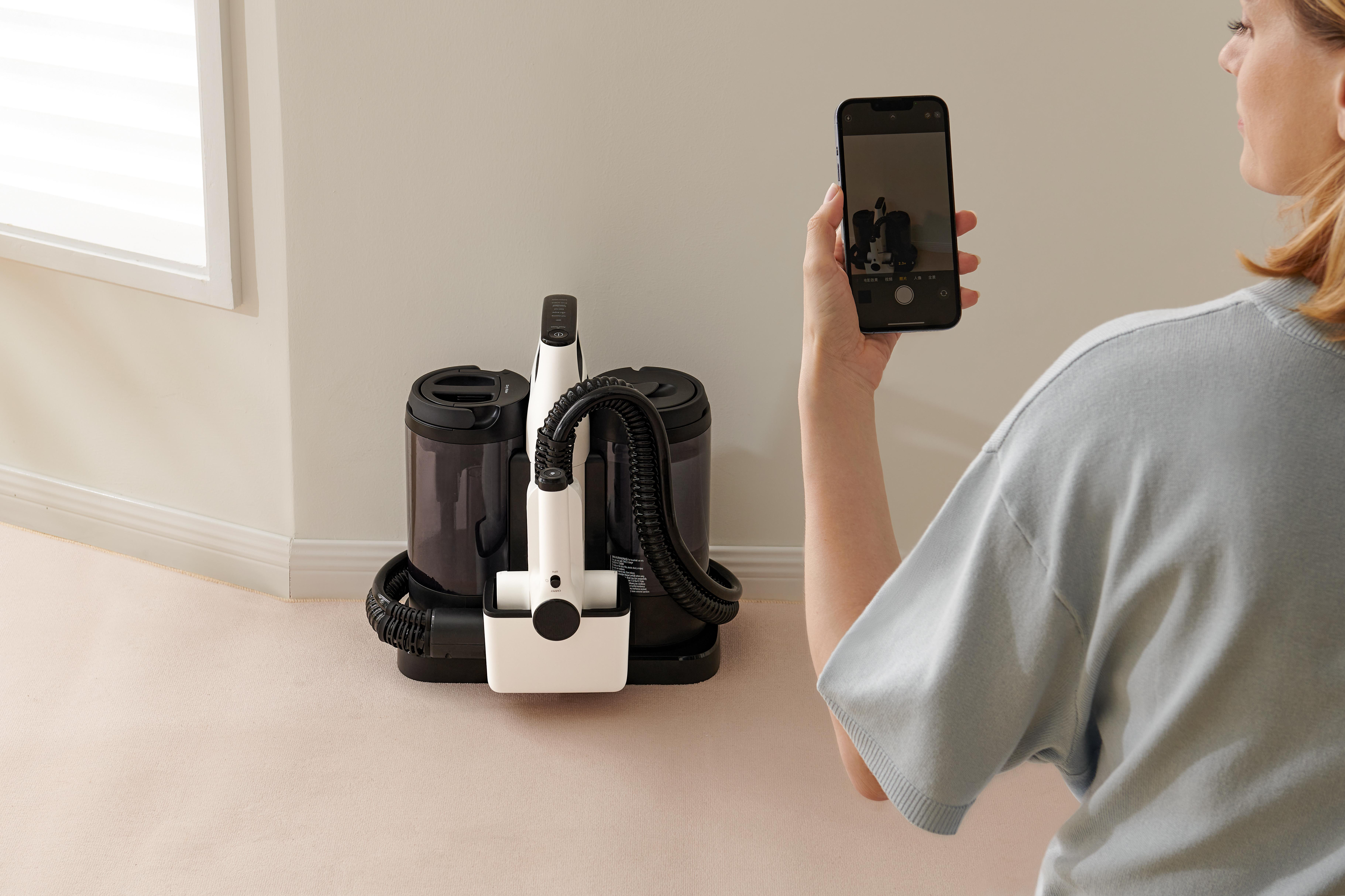 Eine Frau fotografiert eine Reinigungsmaschine mit einem Smartphone.