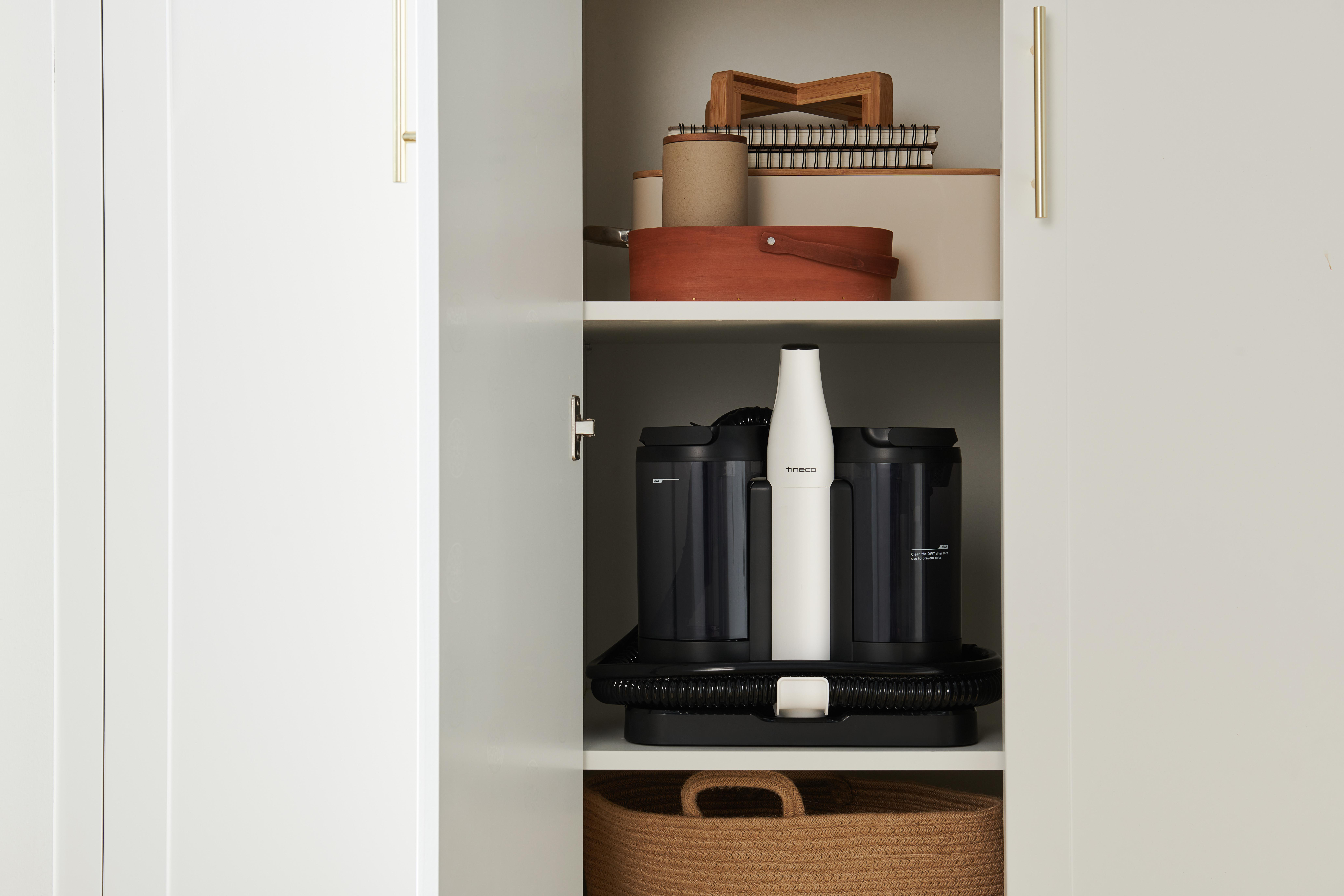 Ein Staubsauger in einem Schrank mit anderen Gegenständen auf Regalen.