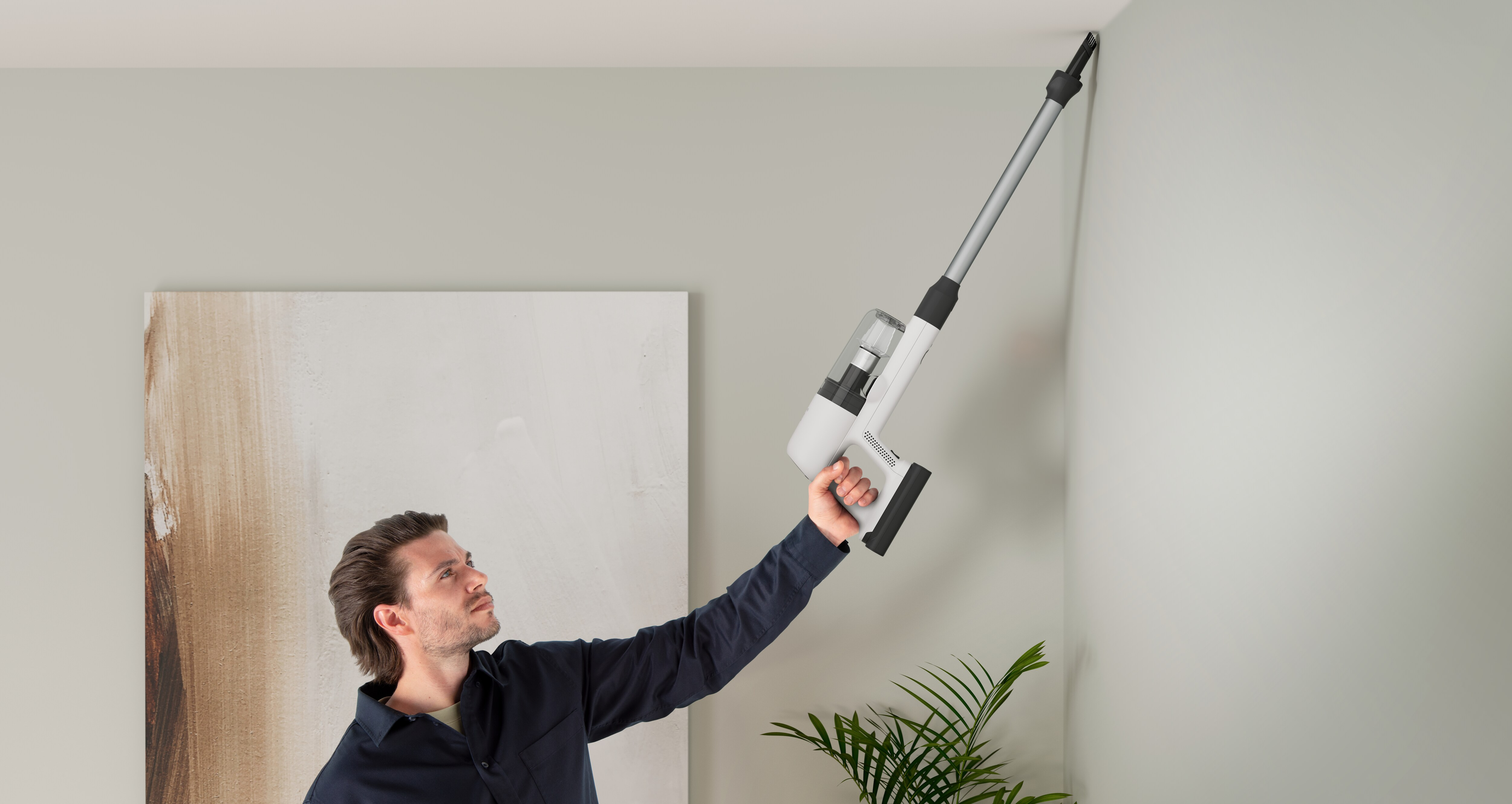 Uomo che usa un aspirapolvere per pulire un angolo del soffitto.