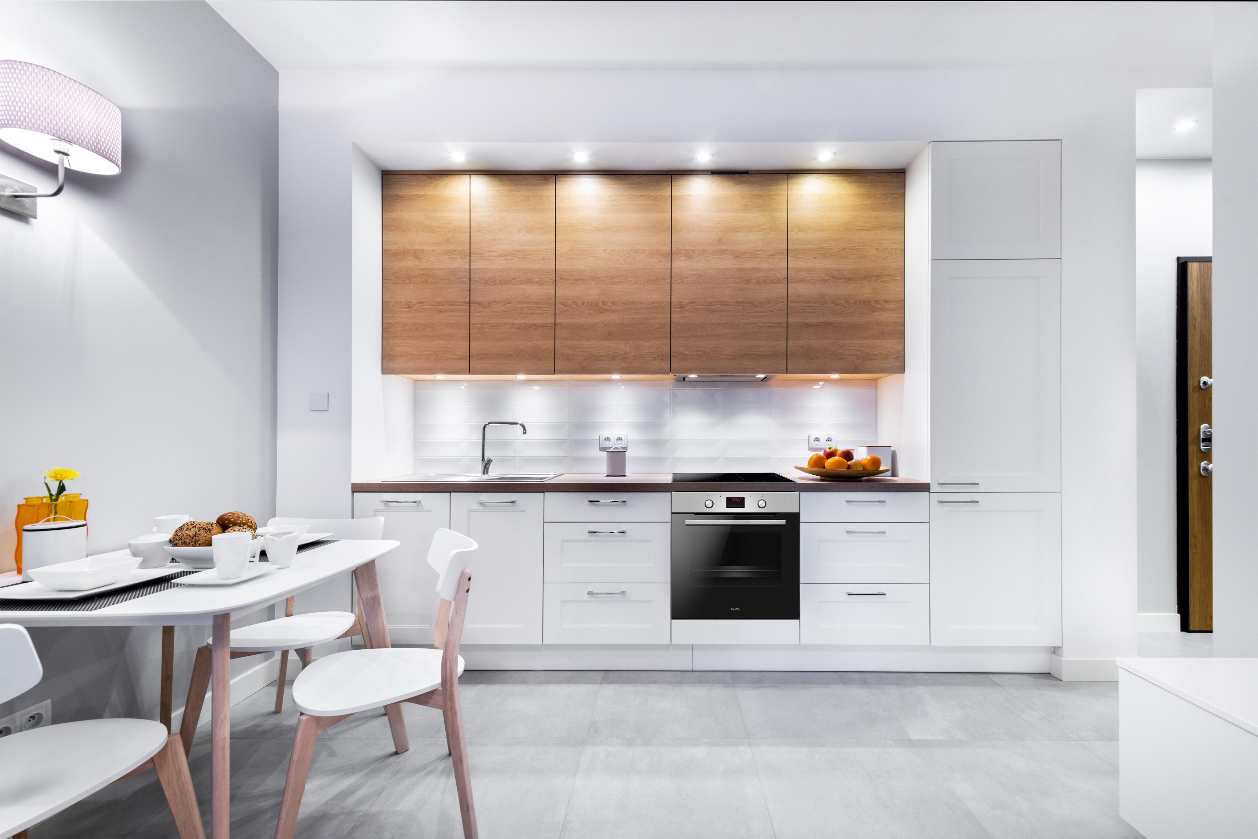 Moderne Küche mit weißen Schränken, Holz-Oberschränken und Esstisch.