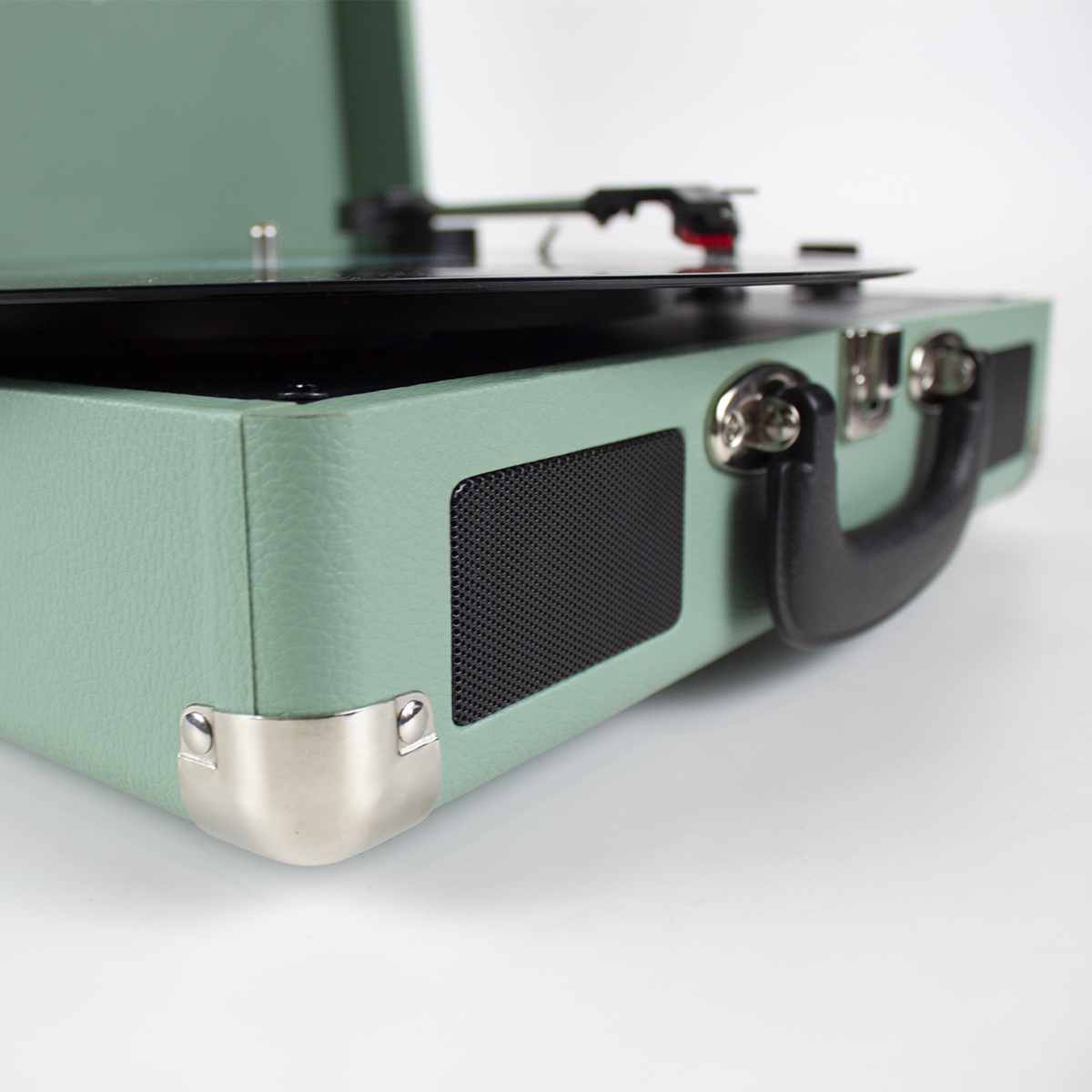 Primer plano de un tocadiscos verde menta, mostrando el altavoz, esquina y asa.