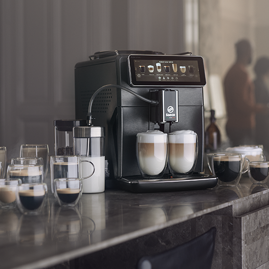 Czarny ekspres do kawy Saeco z filiżankami do kawy na marmurowej powierzchni.