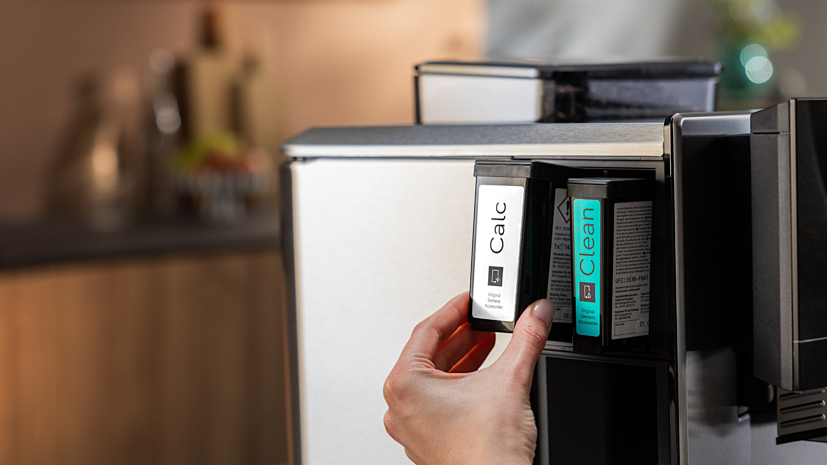 Hand setzt einen sauberen Filter in eine Kaffeemaschine ein. Saubere und Calc-Filter sichtbar.