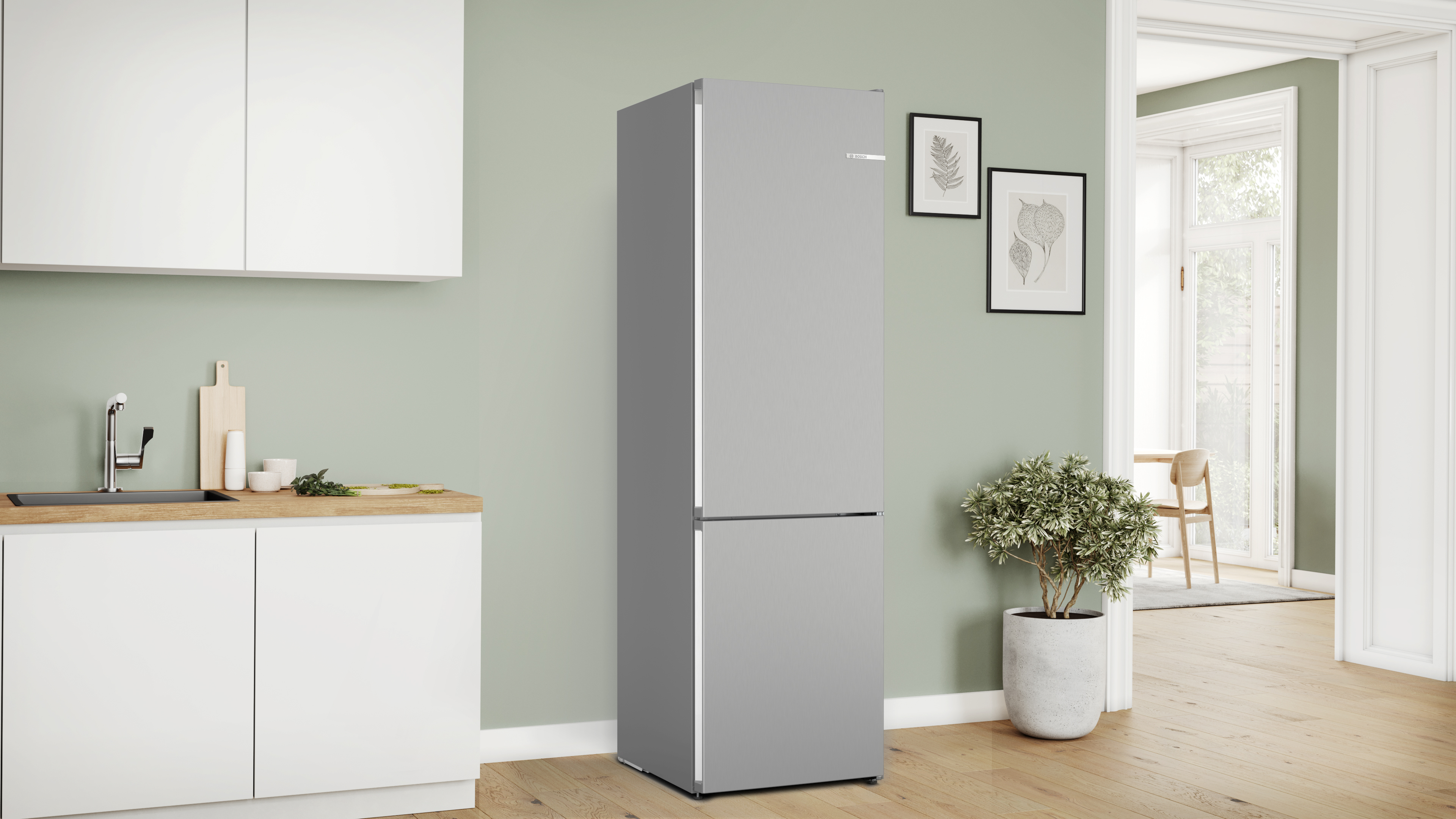 Grauer Kühlschrank in einer Küche mit weißen Schränken und hellgrüner Wand. Dekorative Elemente.