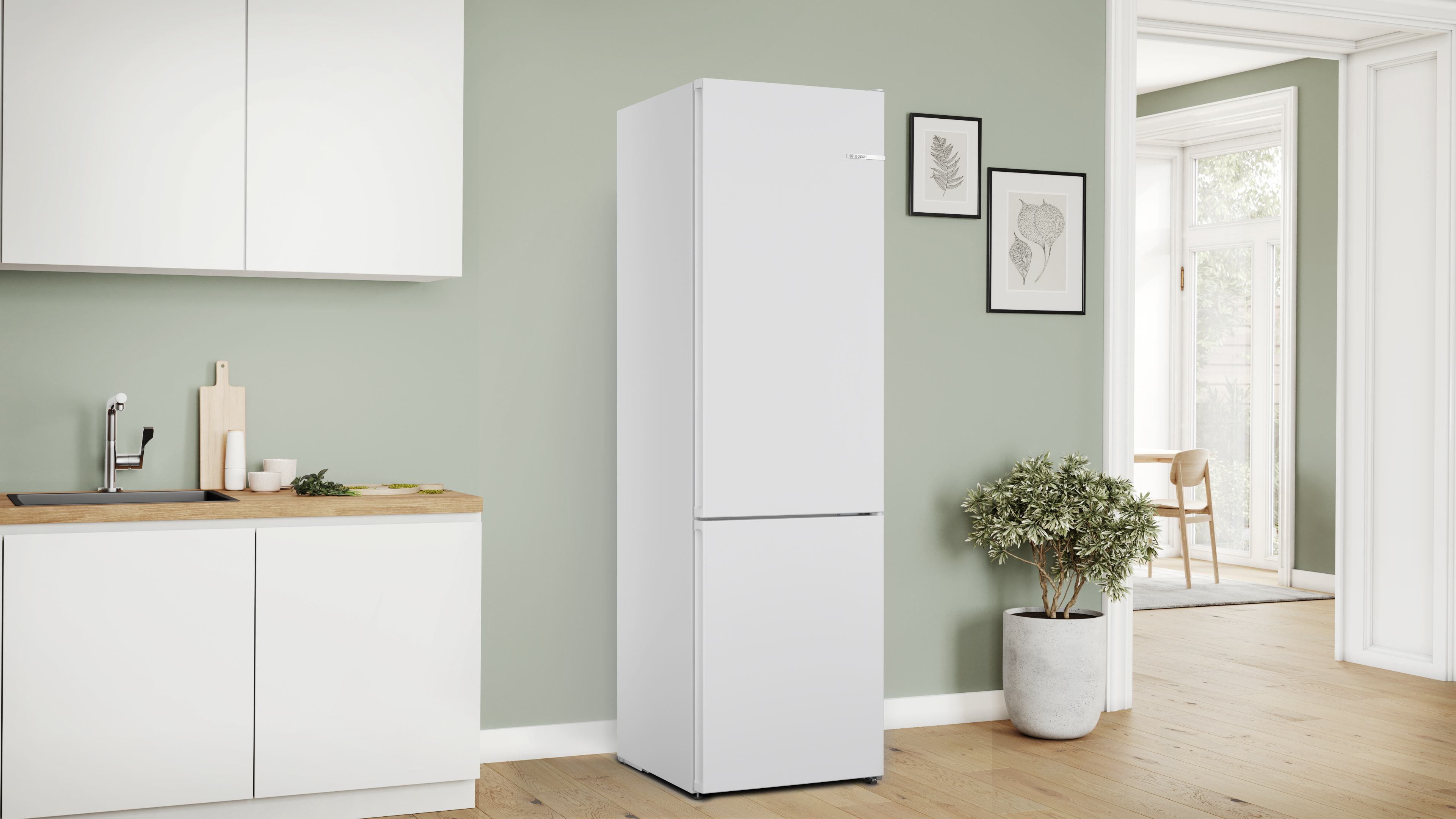 Ein weißer Kühlschrank in einer Küche mit weißen Schränken und grüner Wand.