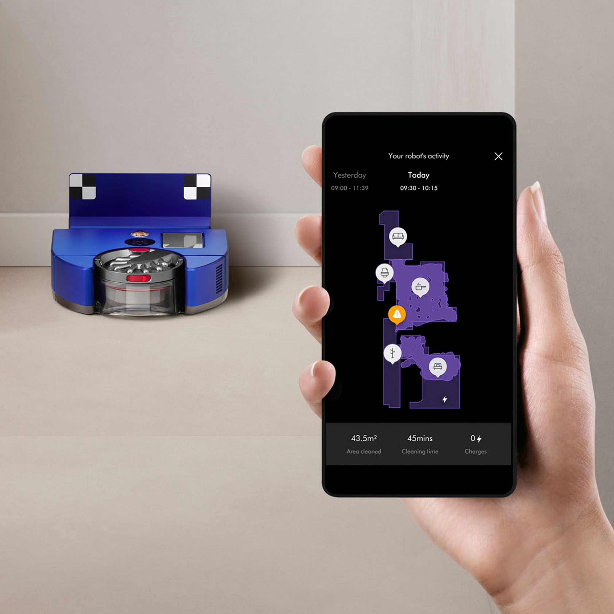 Une main tient un tél éphone affichant une carte de nettoyage. À gauche, un robot aspirateur bleu.