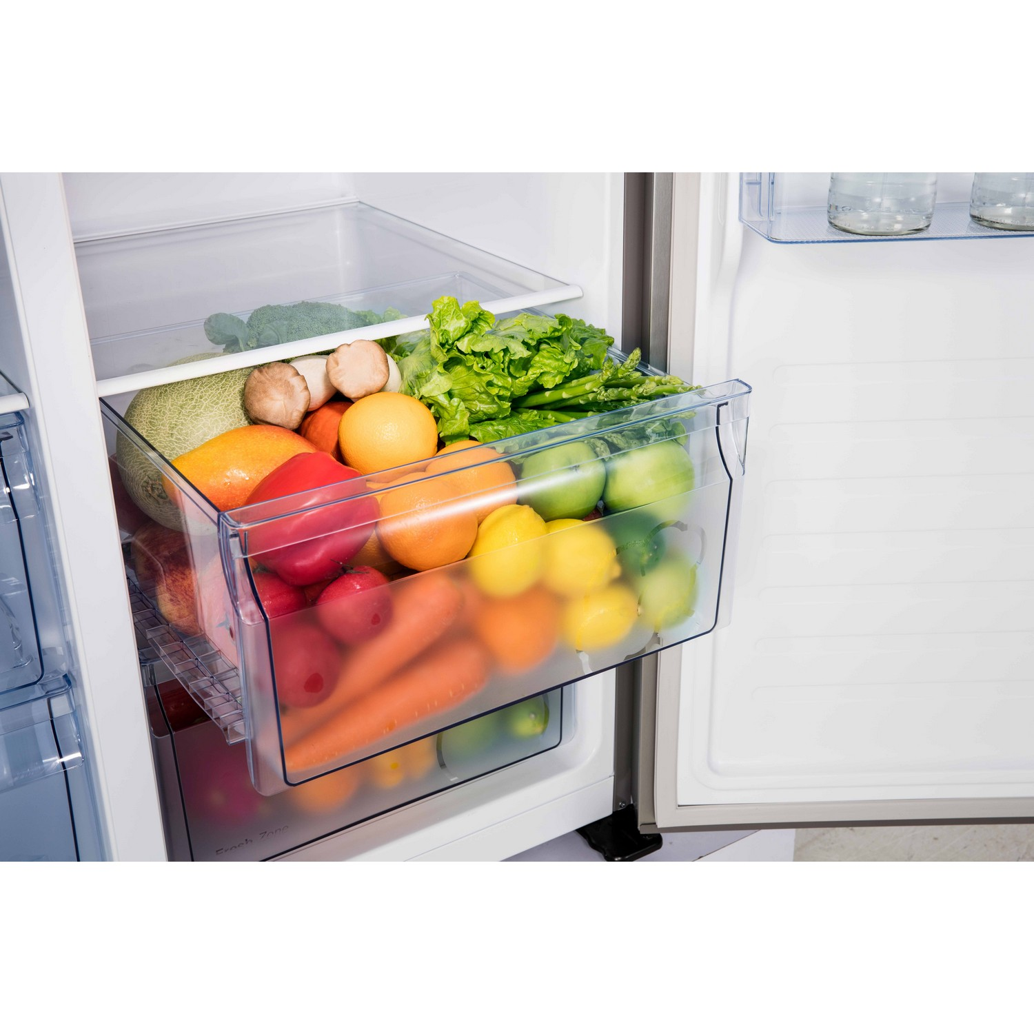 Inside a refrigerator drawer full of fruits and vegetables. Oranges, lemons, and green vegetables.