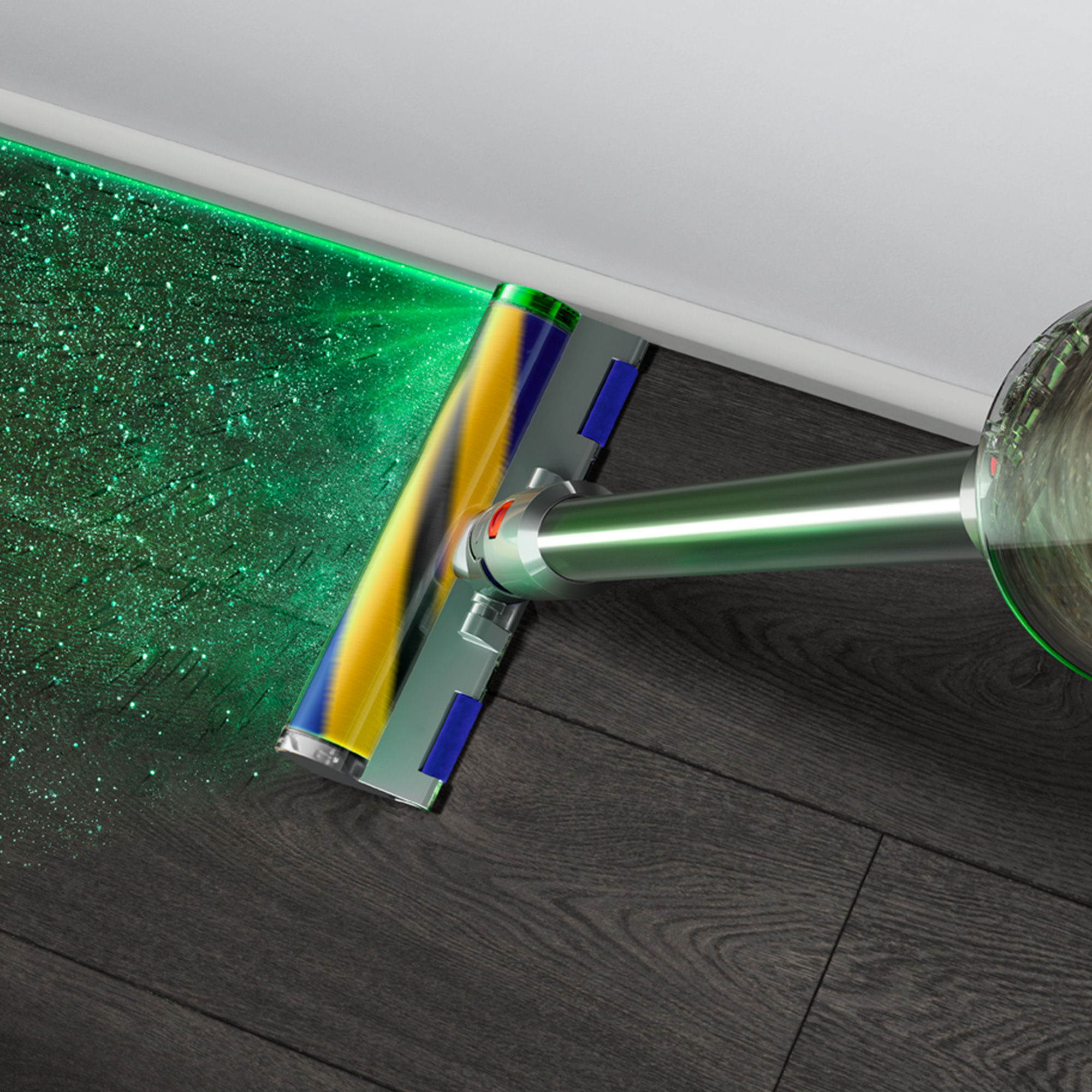 Nahaufnahme des Staubsaugerkopfs mit grünem Laserlicht auf Holzboden, Staubpartikel zeigend.