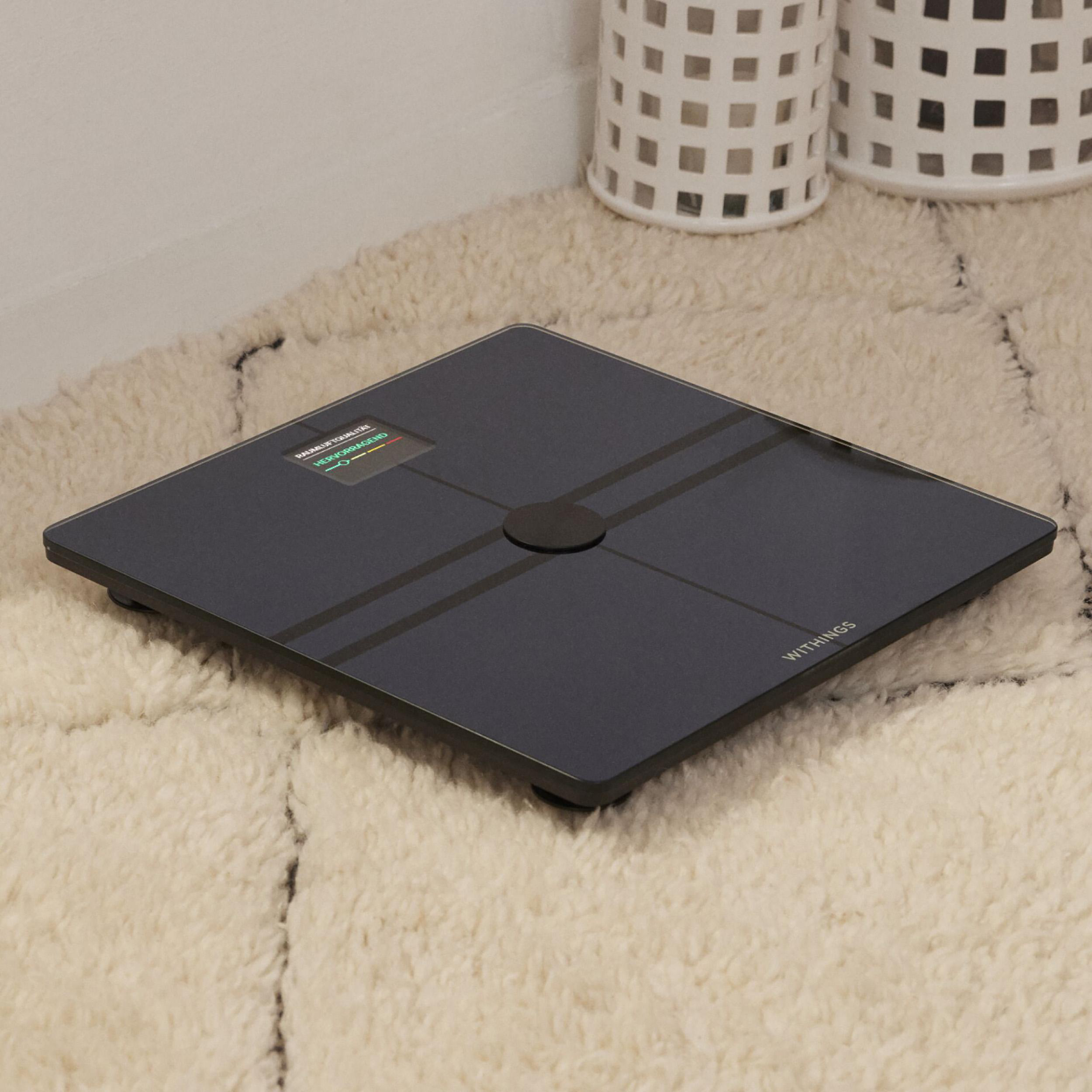 Digitale Waage auf einem flauschigen Teppich. Schwarze Oberfläche mit Display.