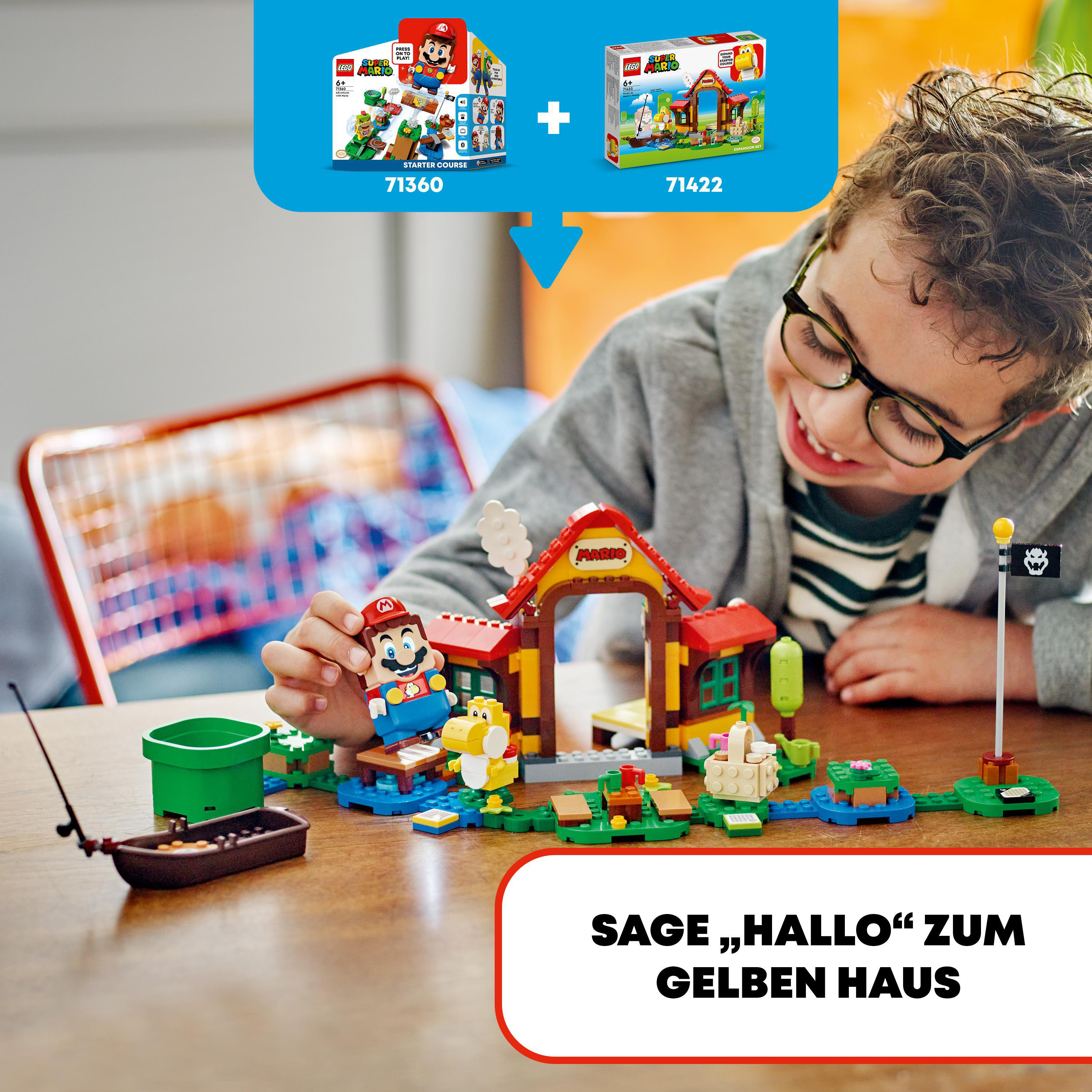 Junge lächelt und schaut auf ein LEGO Mario Set mit Boot und Gebäude.