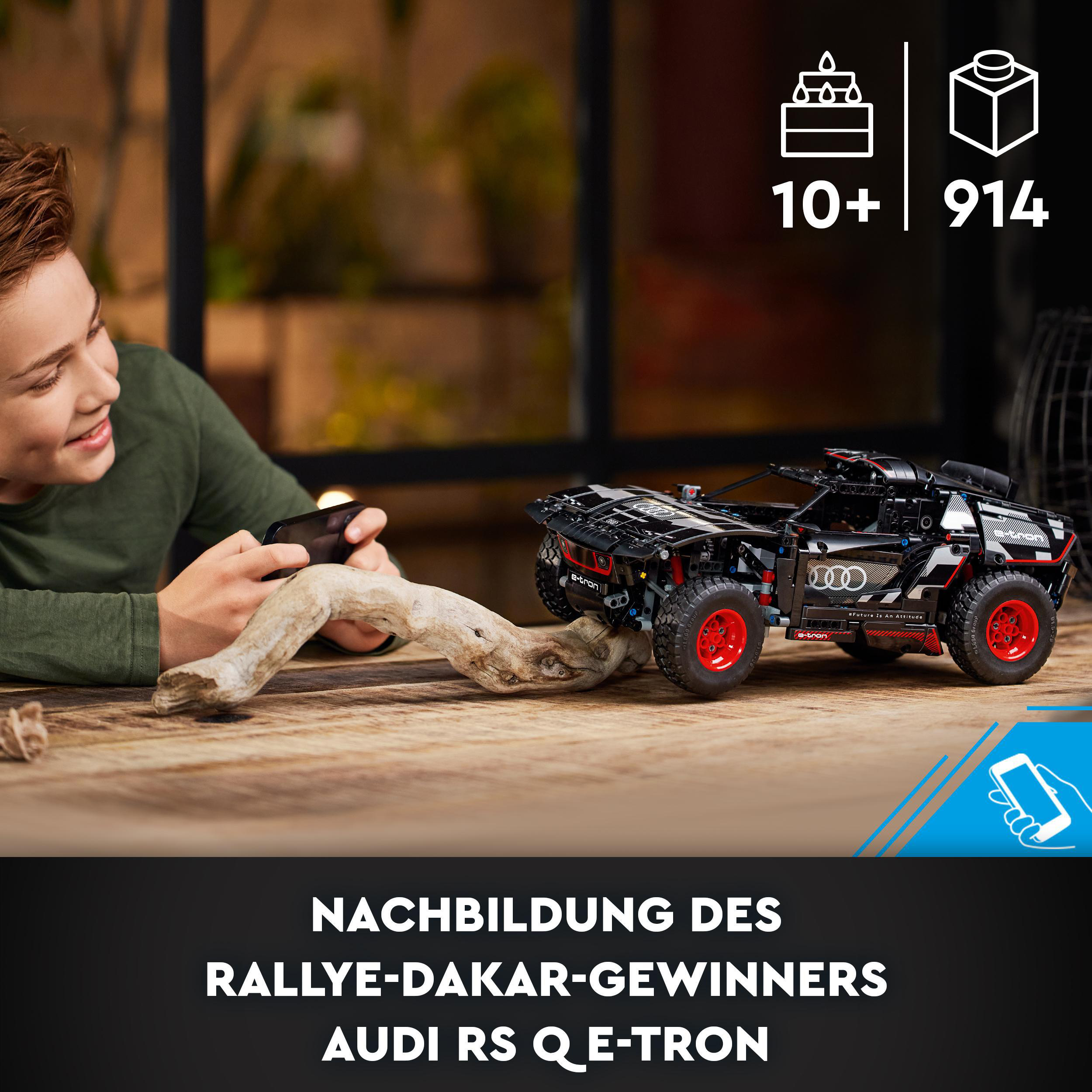 Ein Junge benutzt ein Telefon, um ein Lego-Auto zu steuern. Text und Legosteine sind sichtbar.