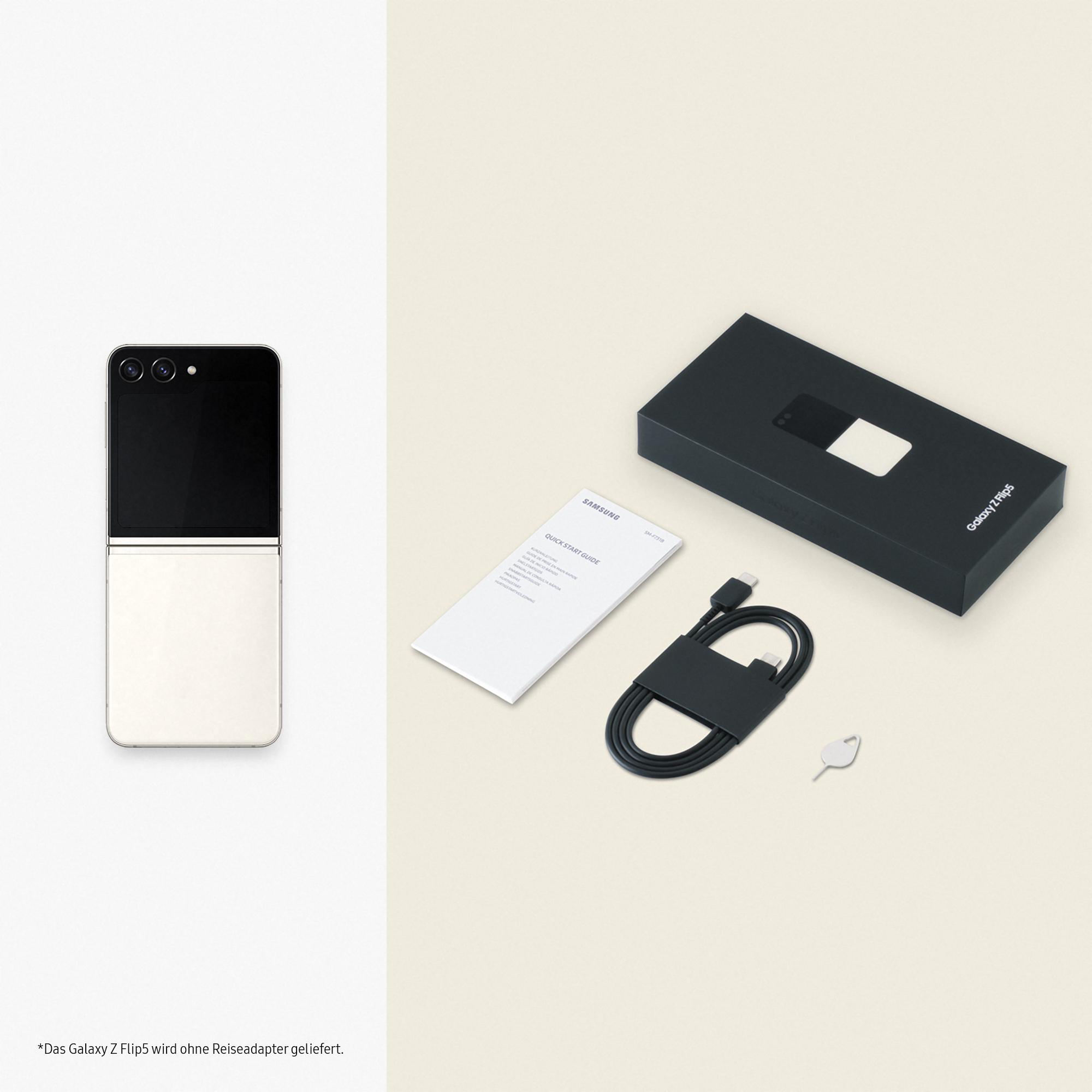 Ein gefaltetes schwarz-weißes Telefon liegt neben seiner Box, einem Kabel und einem Schlüssel.