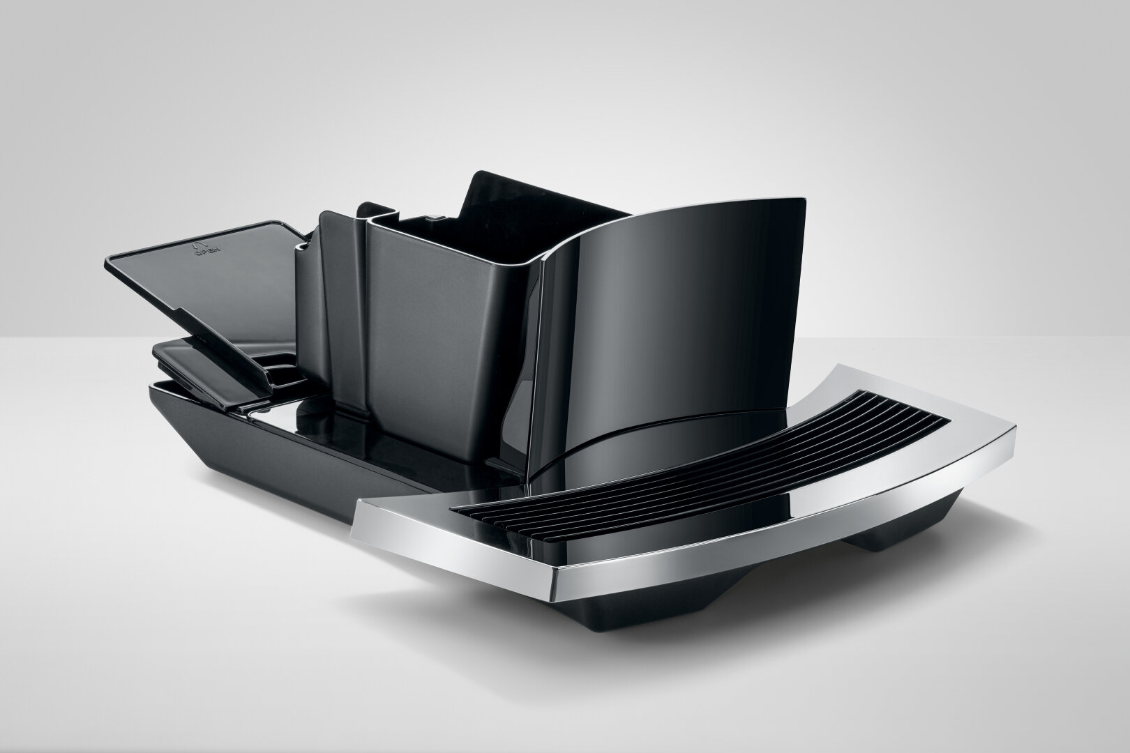 Czarny zbiornik na wodę i tacka ekspresu do kawy, z błyszczącym wykończeniem, na białej powierzchni.