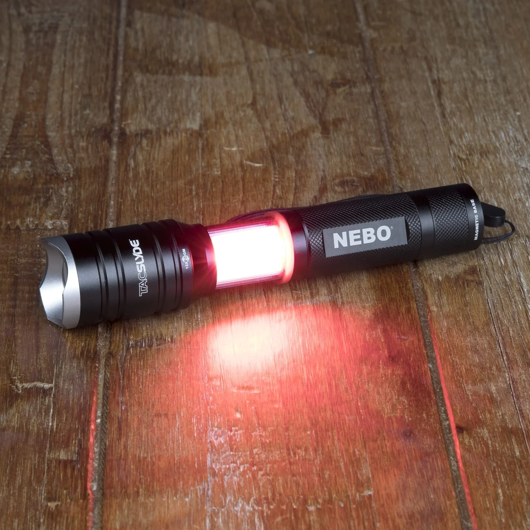 Eine schwarze Taschenlampe mit rotem Licht in der Mitte, auf einer Holzoberfläche. Die Spitze ist silber.